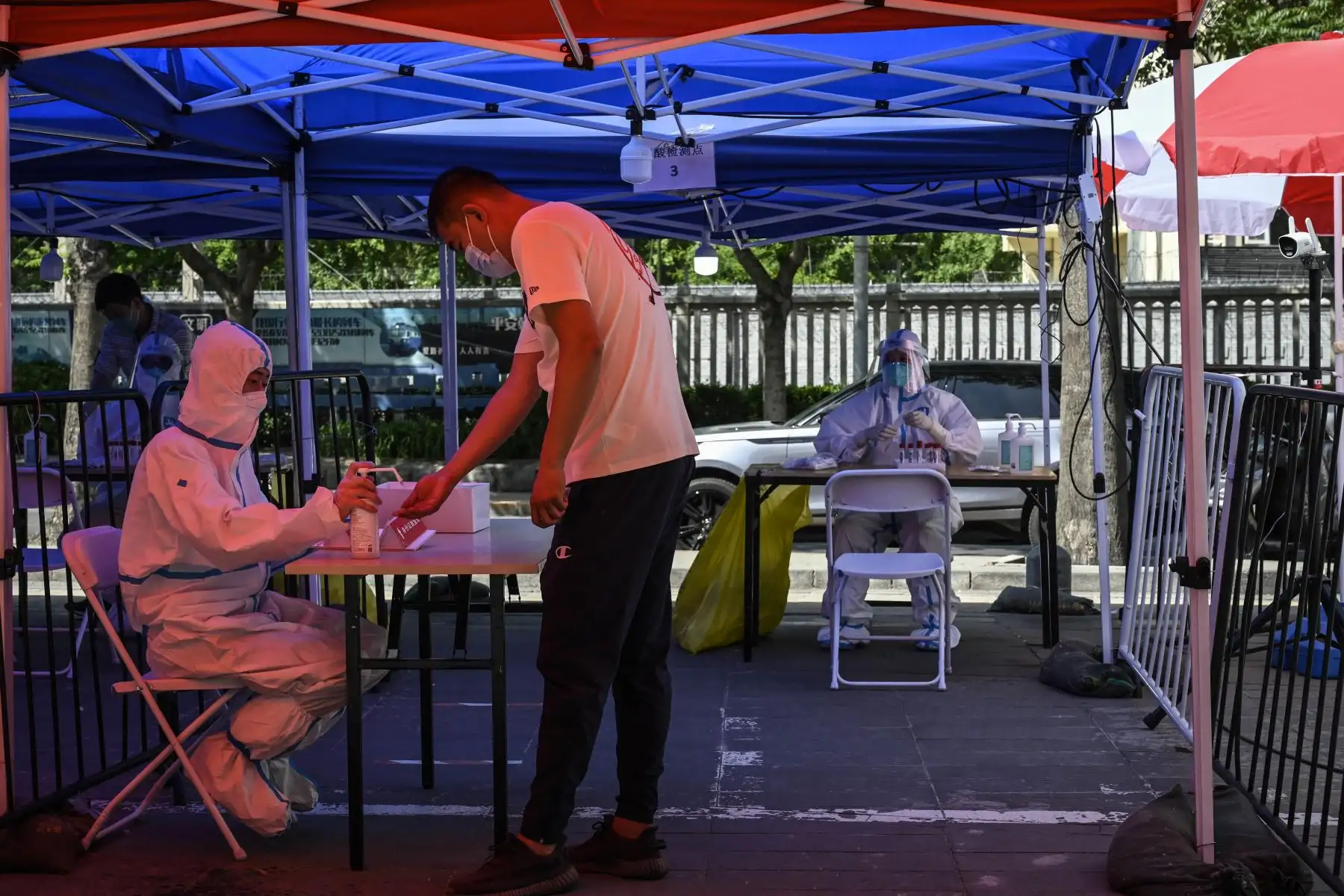Un trabajador de la salud  espera a que las personas se hagan la prueba del coronavirus Covid-19 en un sitio de prueba improvisado afuera de un museo en una calle de Beijing. Foto: AFP