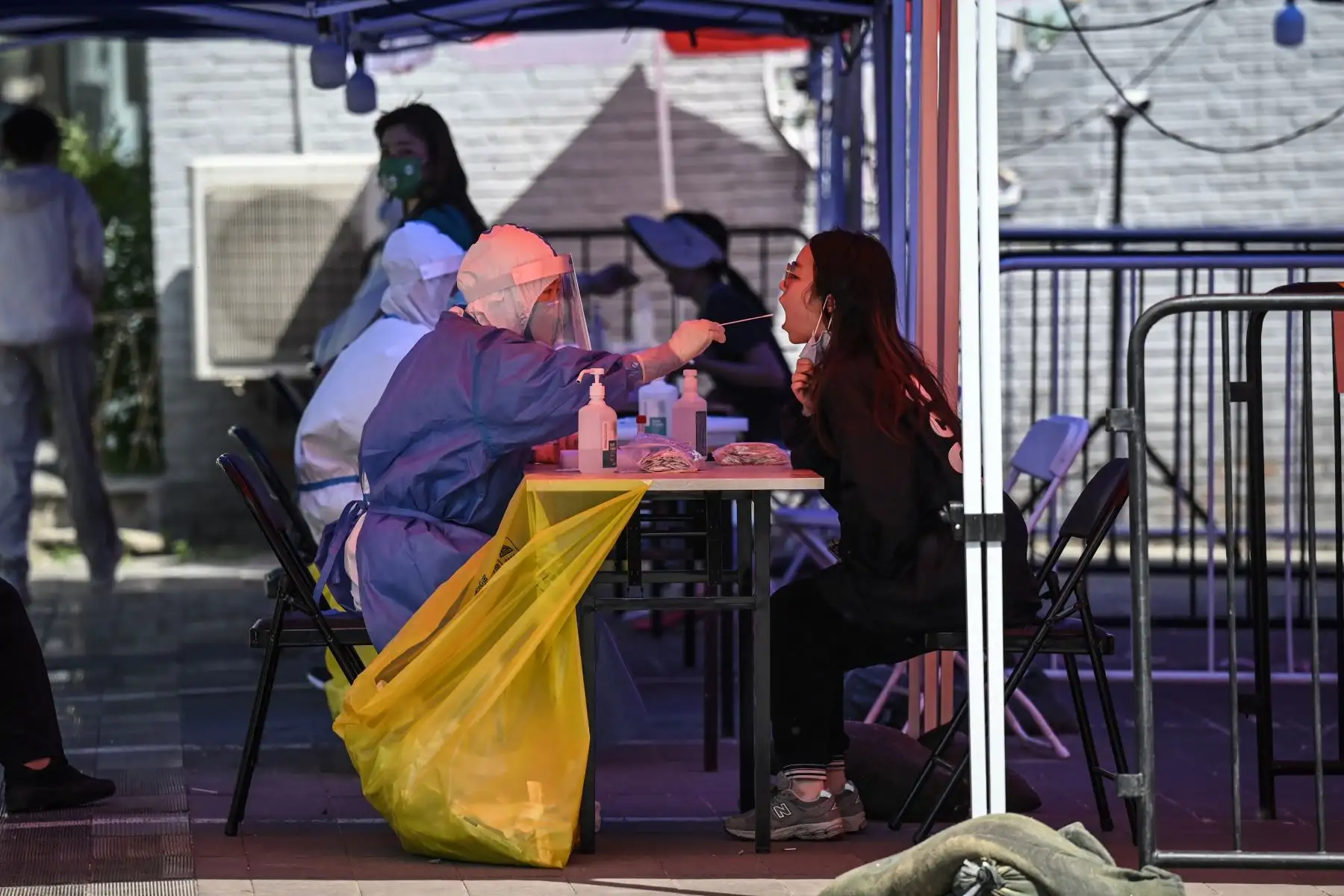 Un trabajador de la salud toma una muestra de hisopo de una mujer para hacerle la prueba del coronavirus Covid-19 en un sitio de prueba improvisado afuera de un museo en una calle de Beijing. Foto: AFP