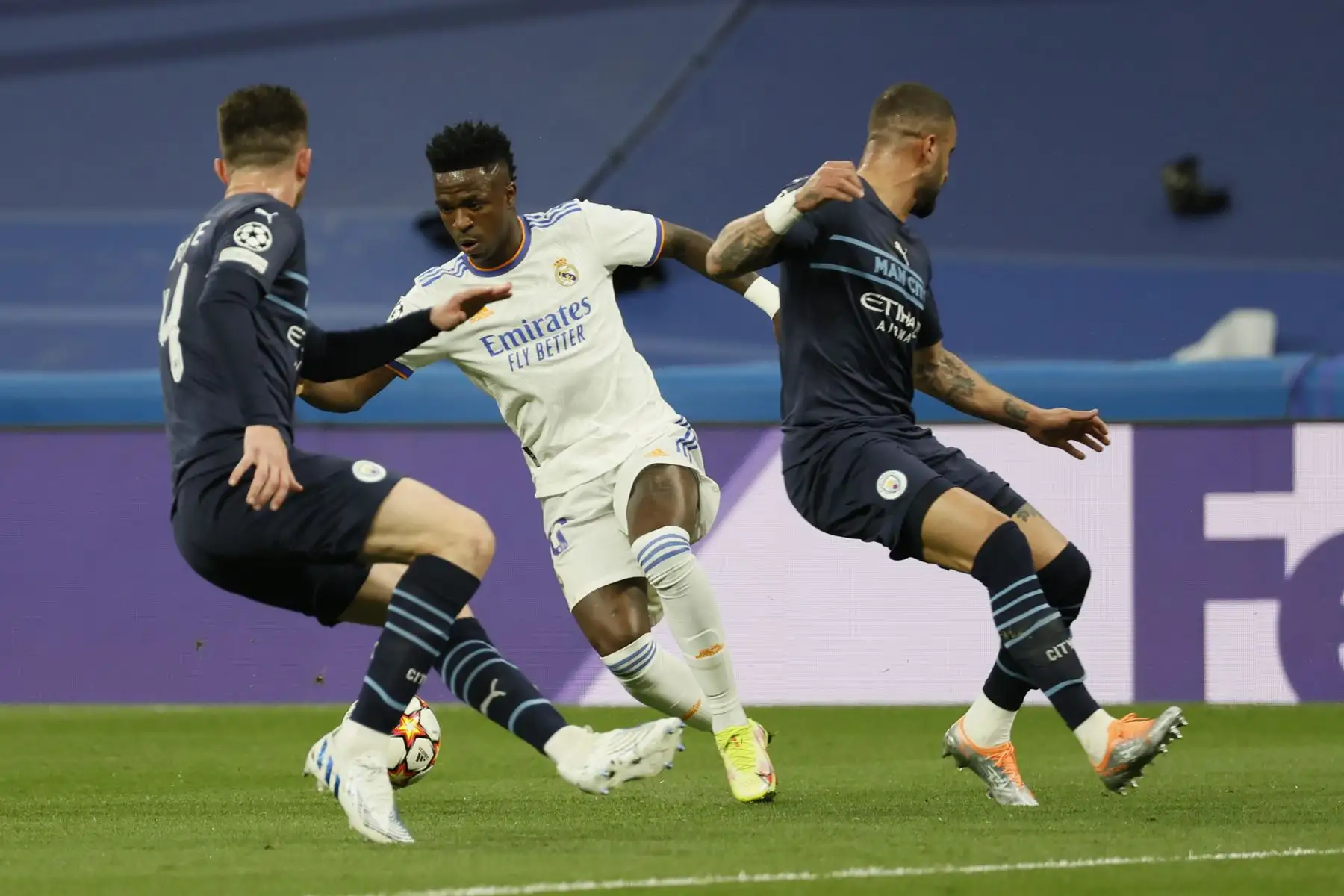 El delantero del Real Madrid Vinicius Jr. (c) intenta superar a los jugadores del Manchester City, durante el partido de semifinales de la Liga de Campeones que Real Madrid y Mancester City disputan este miércoles en el estadio Santiago Bernabéu, en Madrid. EFE/Ballesteros