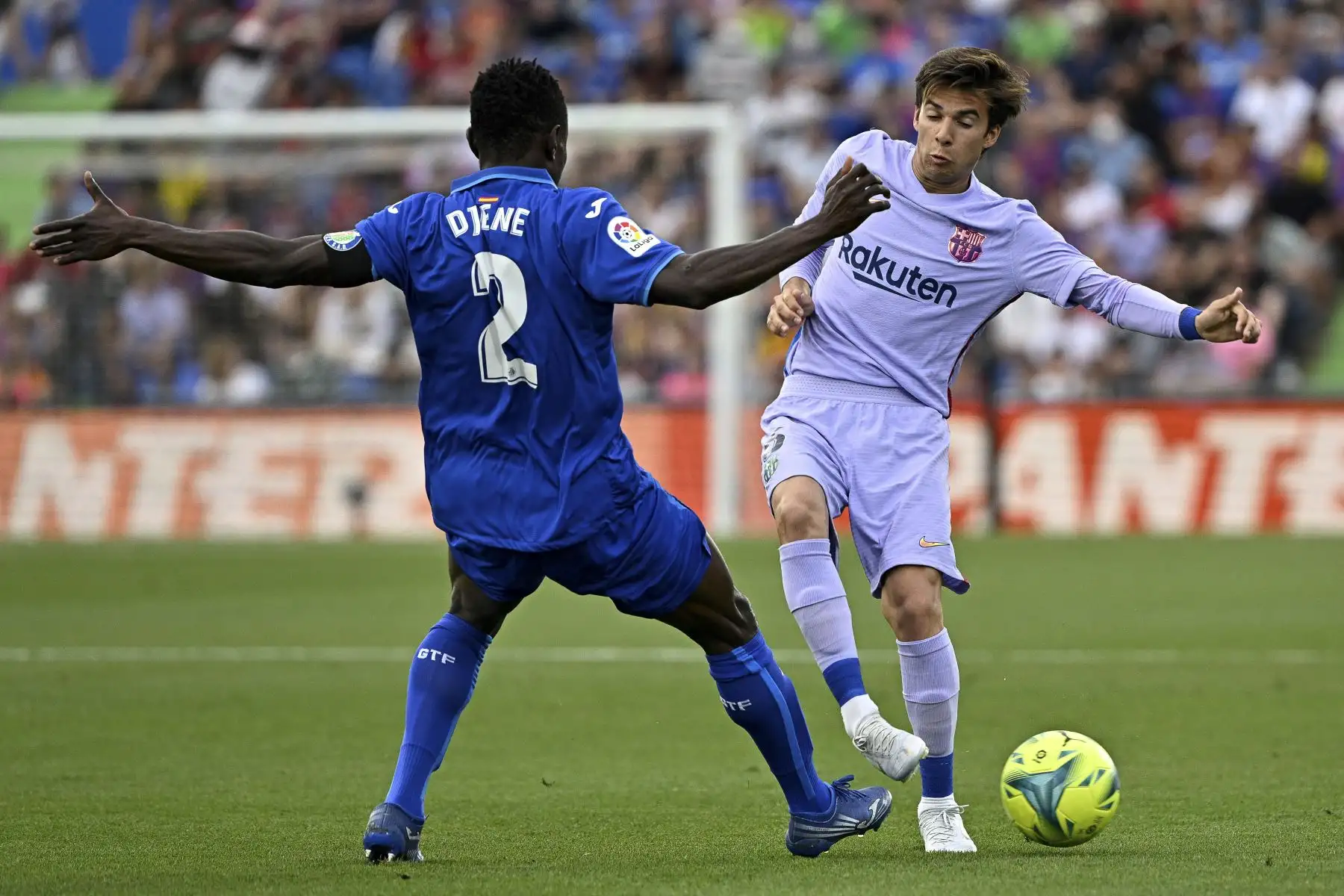 El defensor togolés de Getafe, Djene Dakonam (L), lucha por el balón con el centrocampista español de Barcelona, Riqui Puig, durante el partido de fútbol de la liga española entre el Getafe CF y el FC Barcelona en el estadio Col. Alfonso Pérez de Getafe. Foto: AFP
