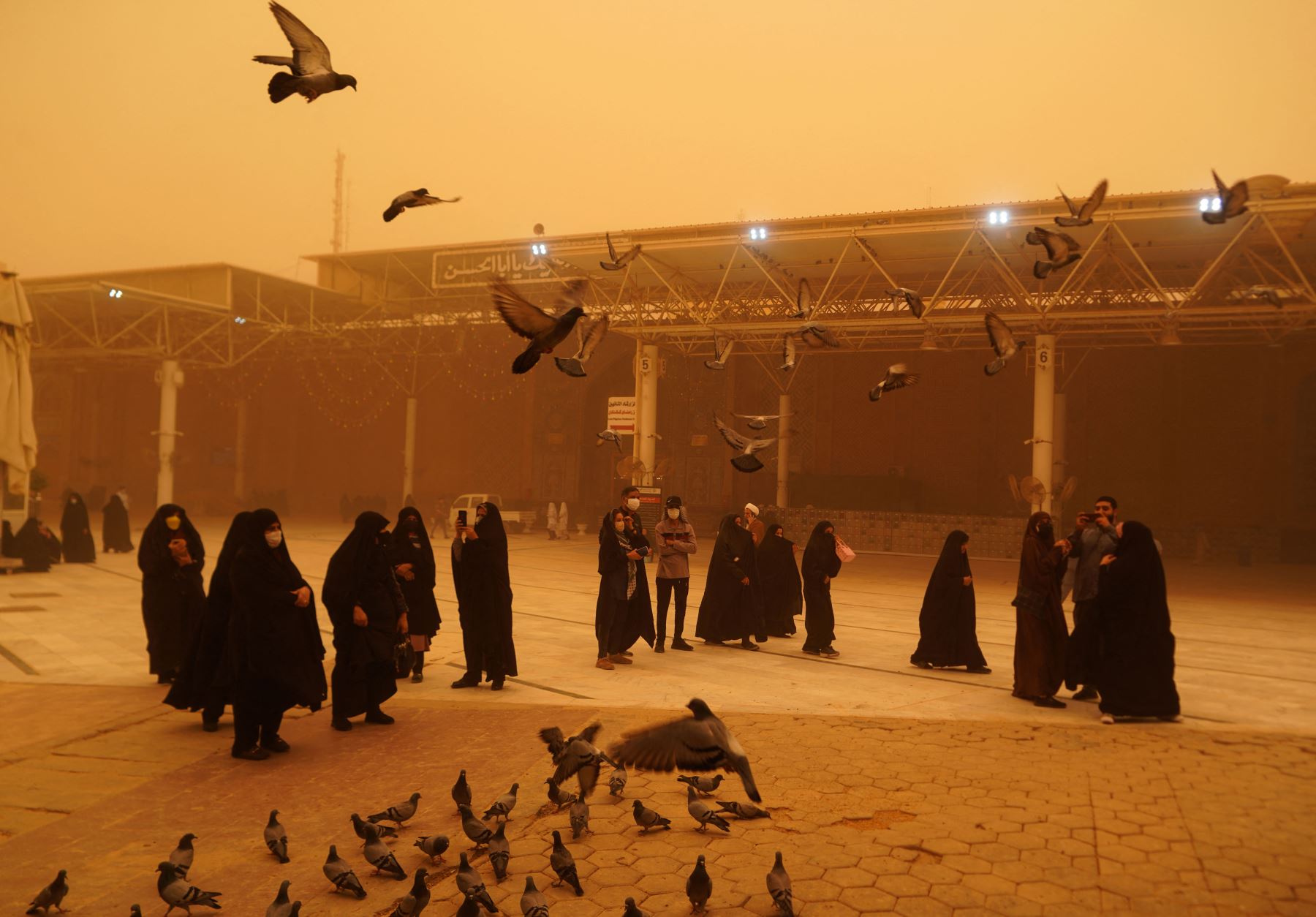 Los visitantes de Irán toman fotografías mientras alimentan a las palomas durante una tormenta de arena en la ciudad santa de Najaf en Irak el 16 de mayo de 2022.
Foto: ANDINA/ AFP