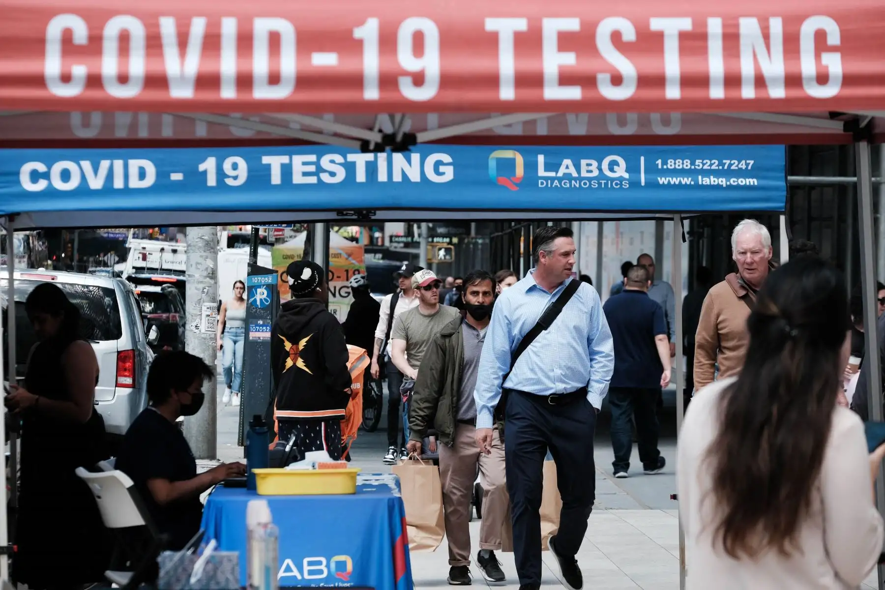 La gente pasa por un sitio de prueba de Covid en la ciudad de Nueva York. El comisionado de salud de Nueva York, el Dr. Ashwin Vasan, pasó de un nivel de alerta de COVID-19 "medio" a un nivel de alerta "alto" en los cinco condados luego de un aumento en los casos. Foto: AFP