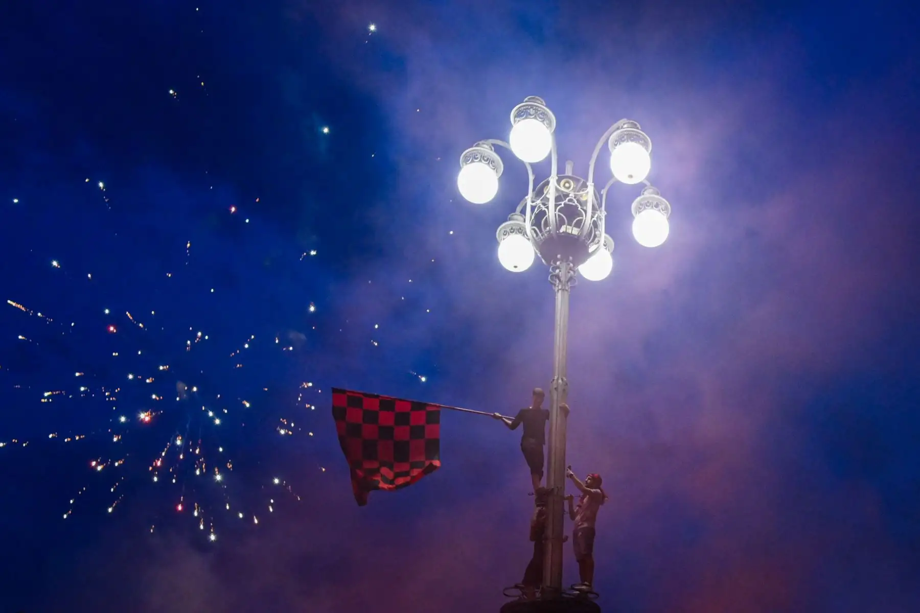 Los fanáticos del AC Milan celebran en una farola en la Piazza Duomo, en el centro de Milán, después ganar el campeonato de la Serie A italiana. Foto. AFP