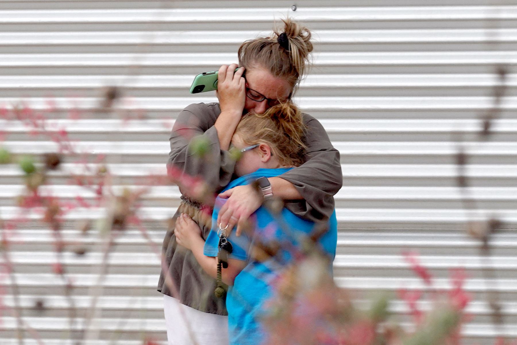 Una mujer llora y abraza a una niña mientras habla por teléfono afuera del Centro Cívico Willie de Leon, donde se ofrecerá asesoramiento de duelo en Uvalde, Texas. Un adolescente armado mató a 18 niños pequeños en un tiroteo en una escuela primaria en Texas, en el tiroteo más mortífero en una escuela de EE. UU. en años. Foto: AFP