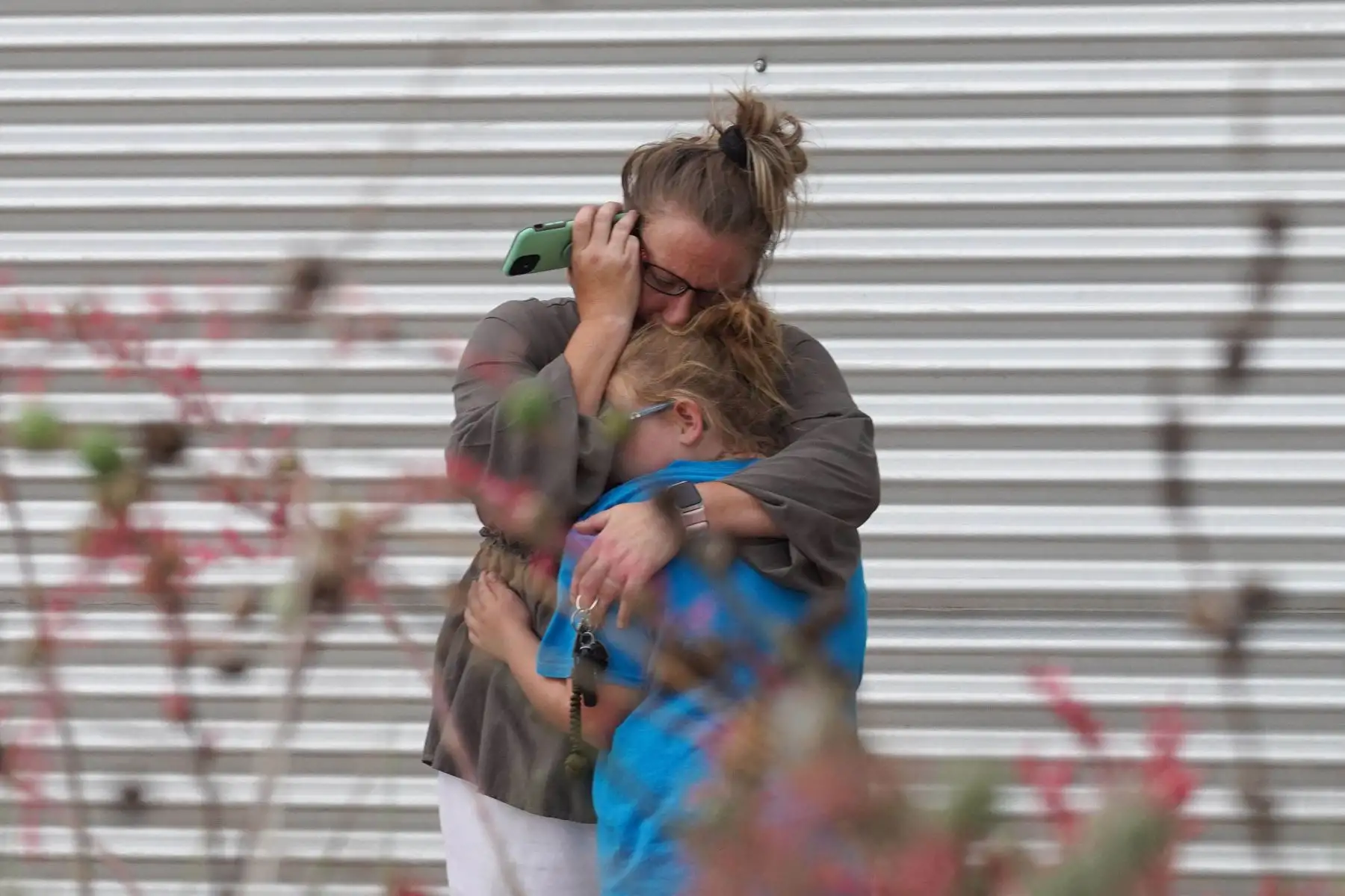Una mujer llora y abraza a una niña mientras habla por teléfono afuera del Centro Cívico Willie de Leon, donde se ofrecerá asesoramiento de duelo en Uvalde, Texas. Un adolescente armado mató a 18 niños pequeños en un tiroteo en una escuela primaria en Texas. Foto: AFP