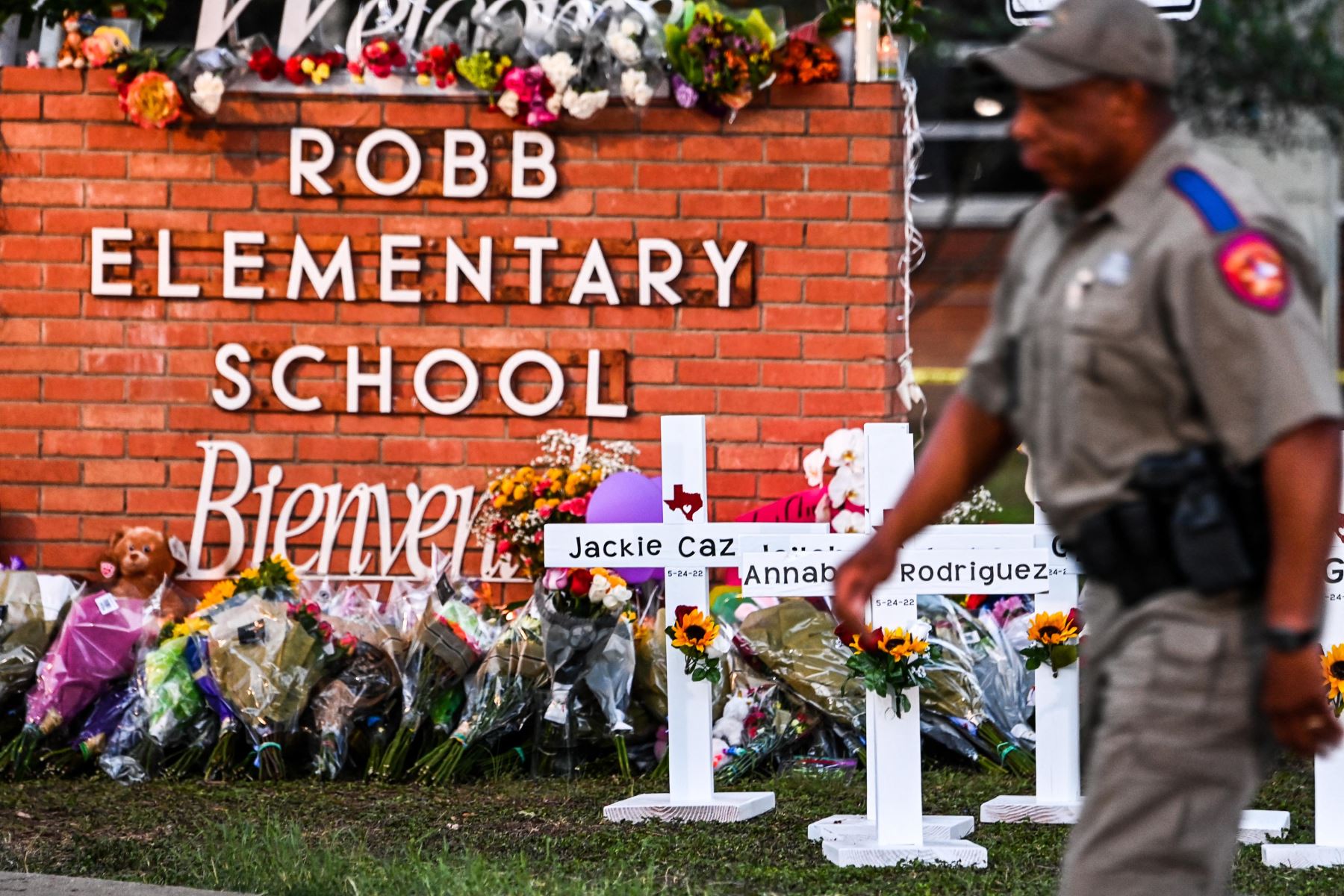 Los oficiales de policía pasan frente a un monumento improvisado para las víctimas del tiroteo en la Escuela Primaria Robb en Uvalde, Texas. Foto: AFP
