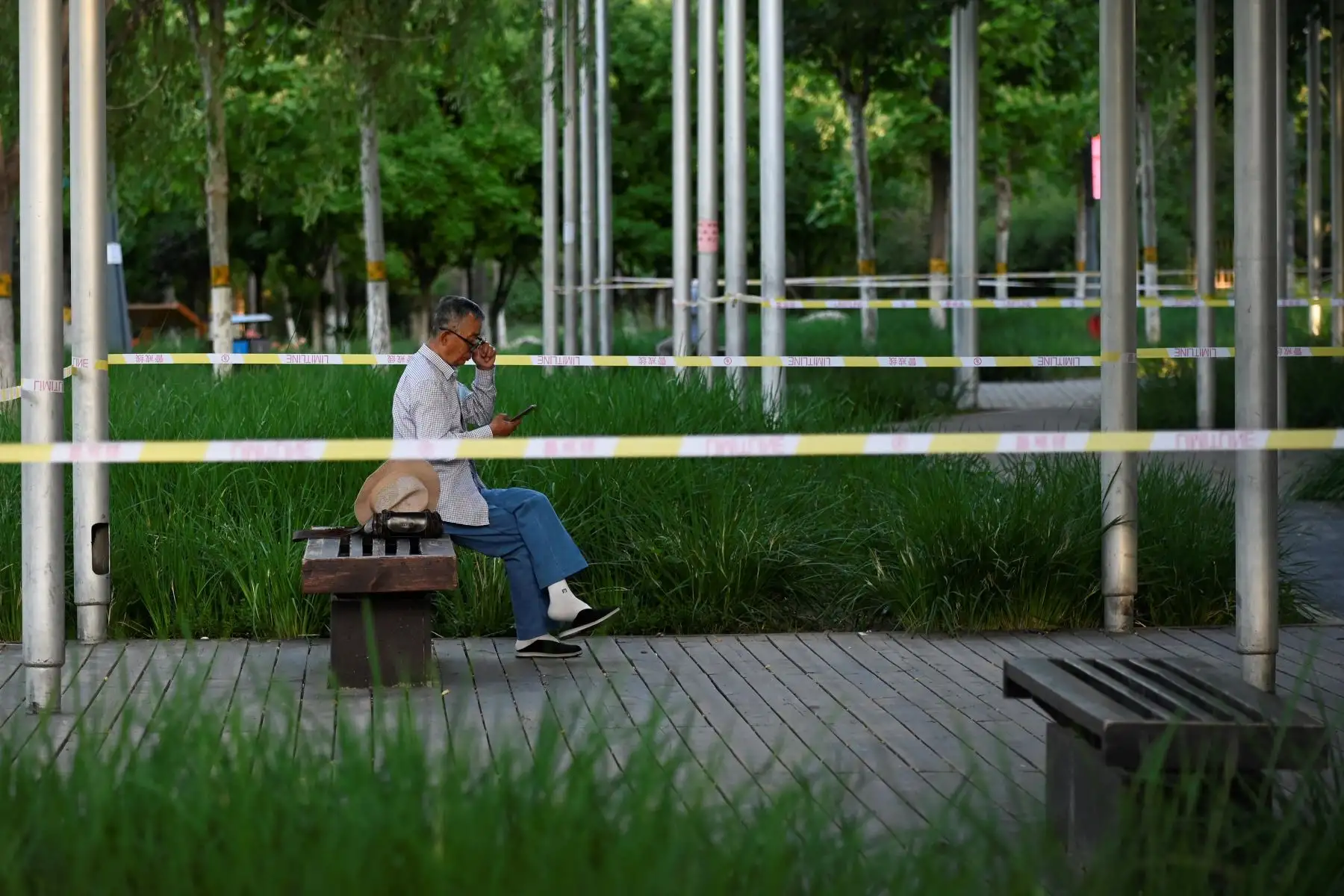 Un anciano usa su teléfono móvil junto a un área acordonada en medio de la pandemia de covid-19 en Beijing