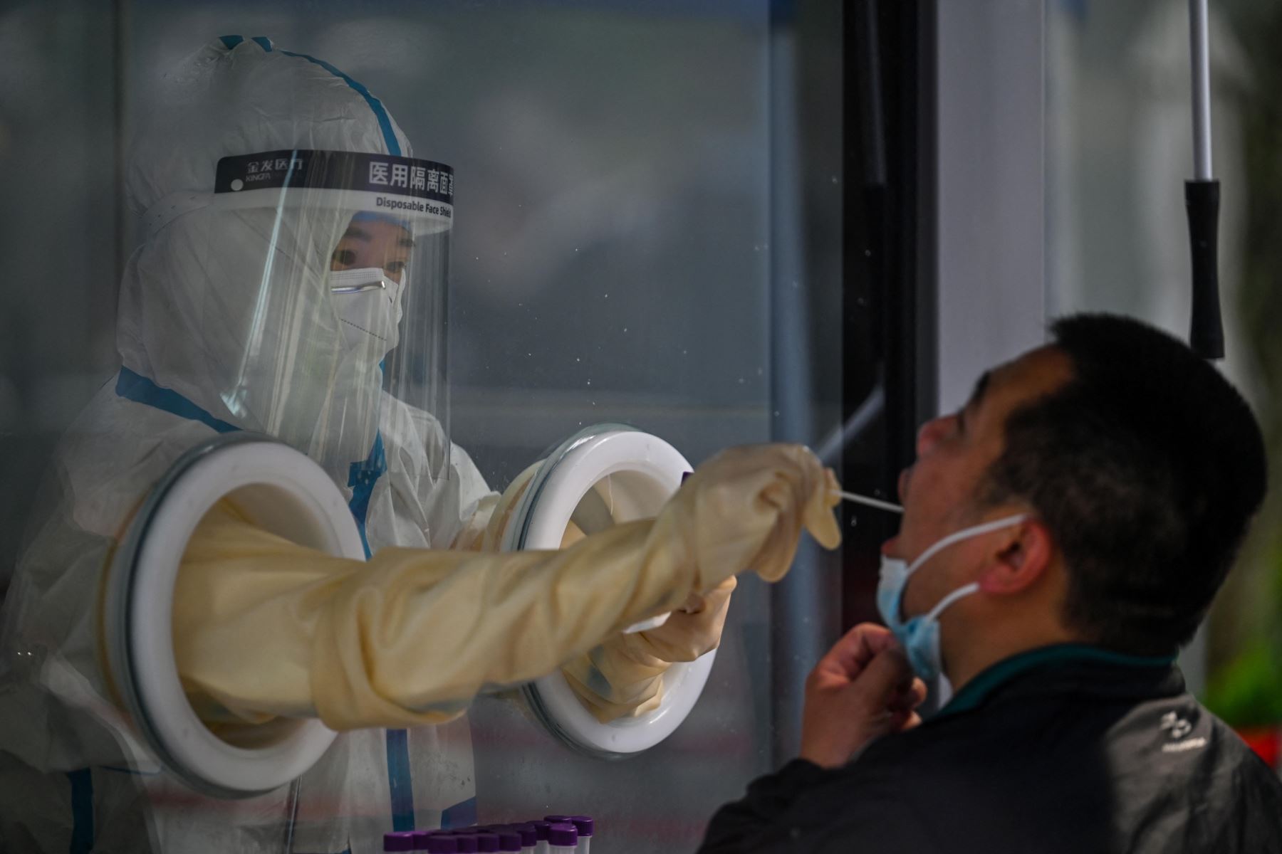Un trabajador de la salud toma una muestra de hisopo de un hombre durante un encierro por coronavirus Covid-19 en el distrito de Jing