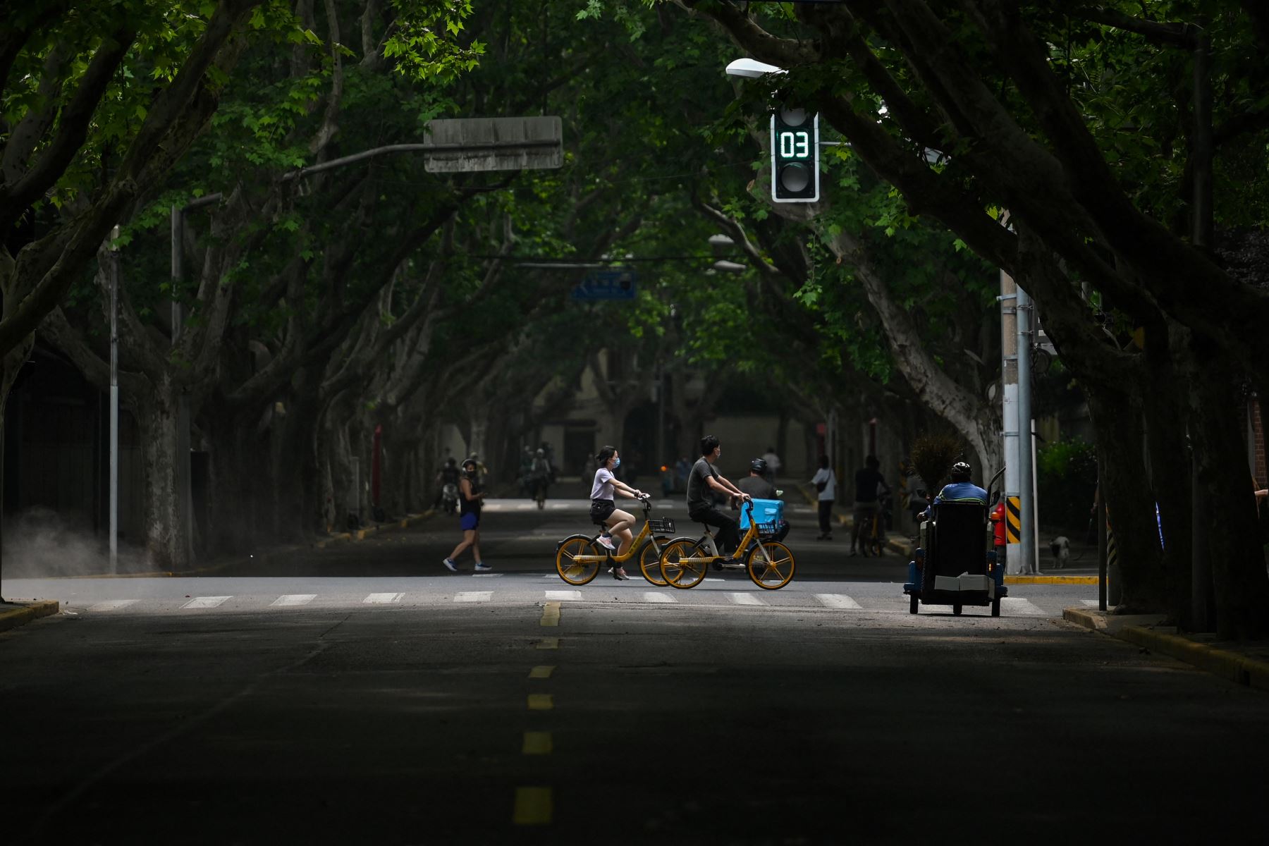 La gente anda en bicicleta por una calle durante el confinamiento por el coronavirus Covid-19 en Shanghái el 27 de mayo de 2022. Foto: AFP