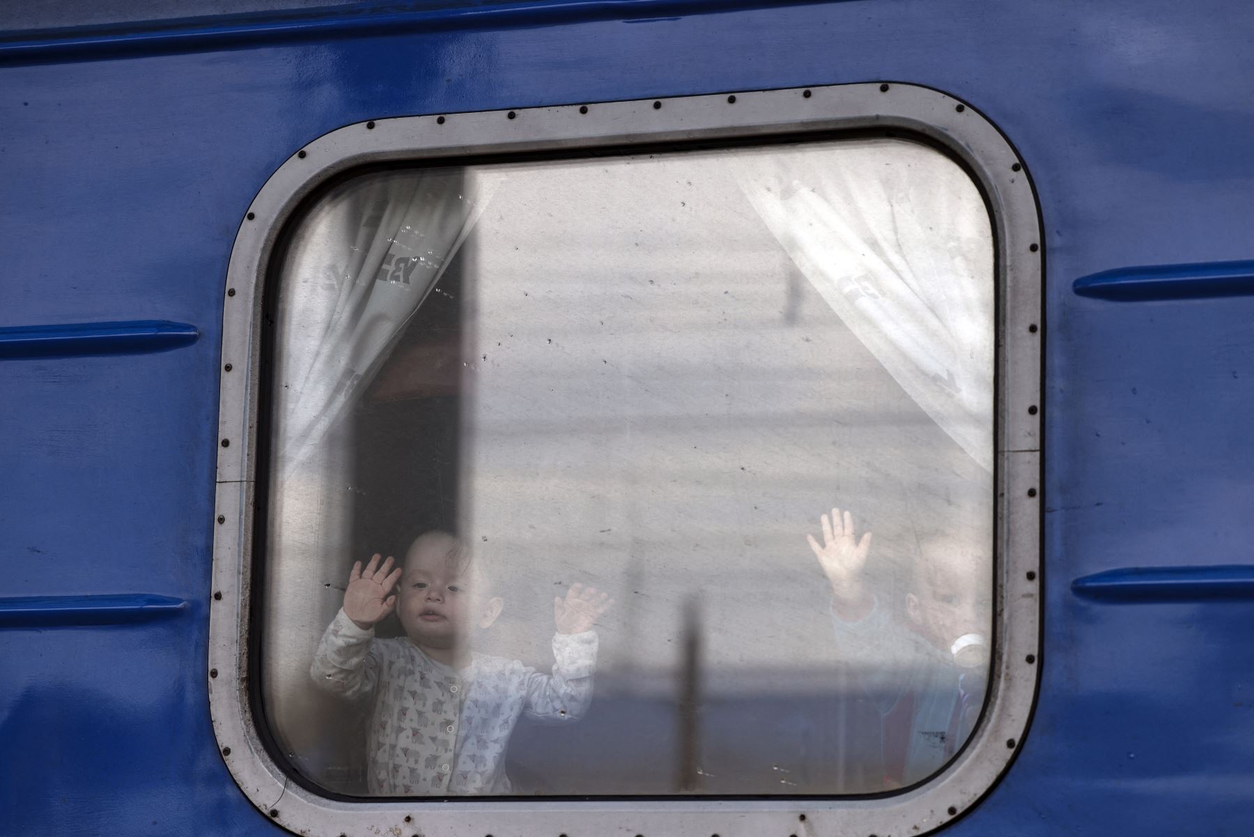 Esta foto de archivo tomada el 12 de abril de 2022, muestra a niños saludando desde un tren en la estación central de Slovyansk, en la región de Donbass, mientras la gente abandona el área en medio de la invasión rusa de Ucrania. Foto: AFP