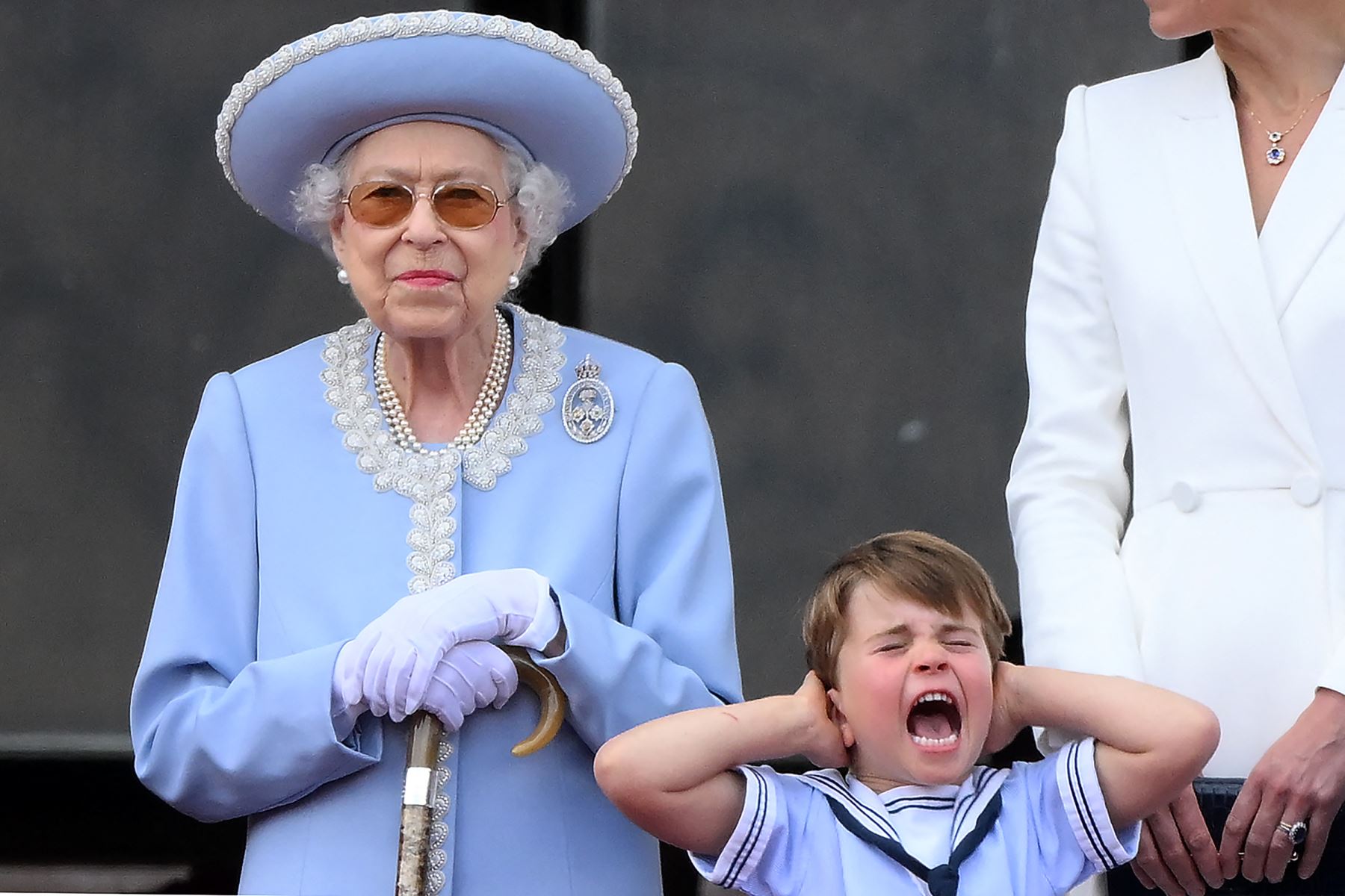 El príncipe Luis de Cambridge (derecha) de Gran Bretaña se tapa las orejas mientras se para junto a la reina Isabel II para ver un vuelo especial desde el balcón del Palacio de Buckingham después del desfile del cumpleaños de la reina, como parte de las celebraciones del jubileo de platino de la reina Isabel II. Foto: AFP