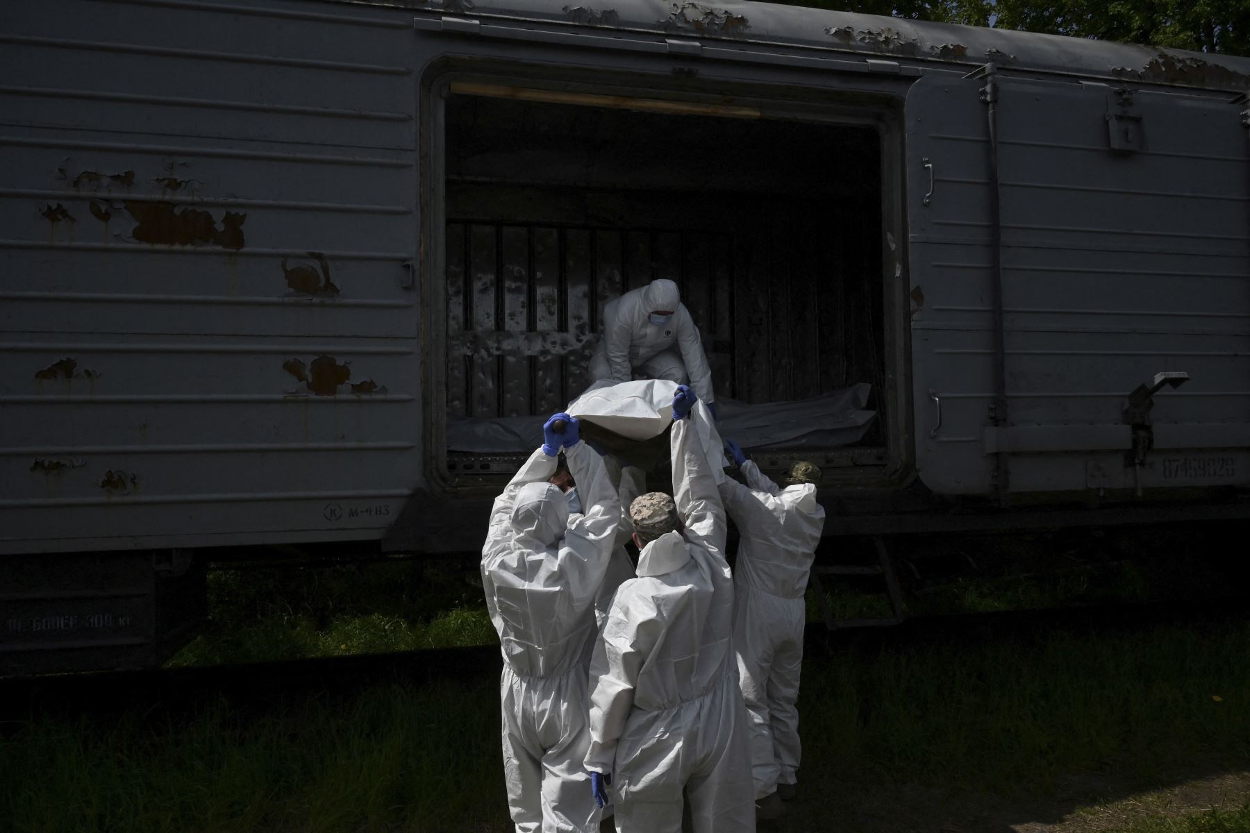 Expertos forenses ucranianos examinan el cuerpo de un soldado ruso exhumado en la aldea de Zavalivka, al oeste de Kyiv, en un vagón de tren refrigerado apilado con los muertos rusos. Foto: AFP