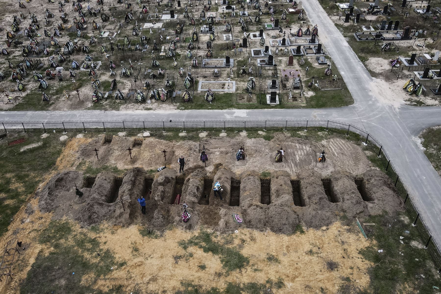 Una fotografía aérea tomada el 18 de abril de 2022 muestra ataúdes enterrados durante una ceremonia fúnebre en un cementerio en Bucha, Ucrania, en medio de la invasión rusa. Foto: AFP