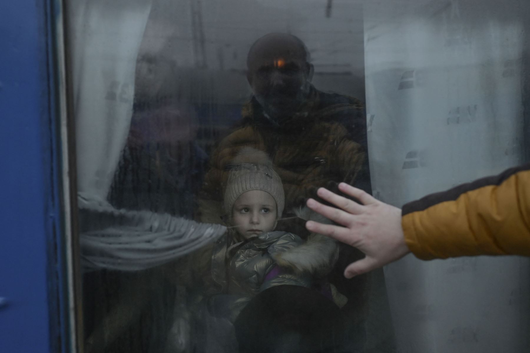 Un padre pone su mano en la ventana mientras se despide de su hija frente a un tren de evacuación en la estación central de trenes de Odessa, Ucrania. Foto: AFP