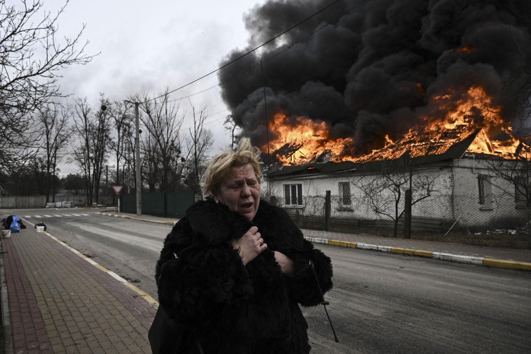 Una mujer reacciona frente a una casa en llamas tras ser bombardeada en la ciudad de Irpin, en las afueras de Kyiv, el 4 de marzo de 2022. Foto: AFP