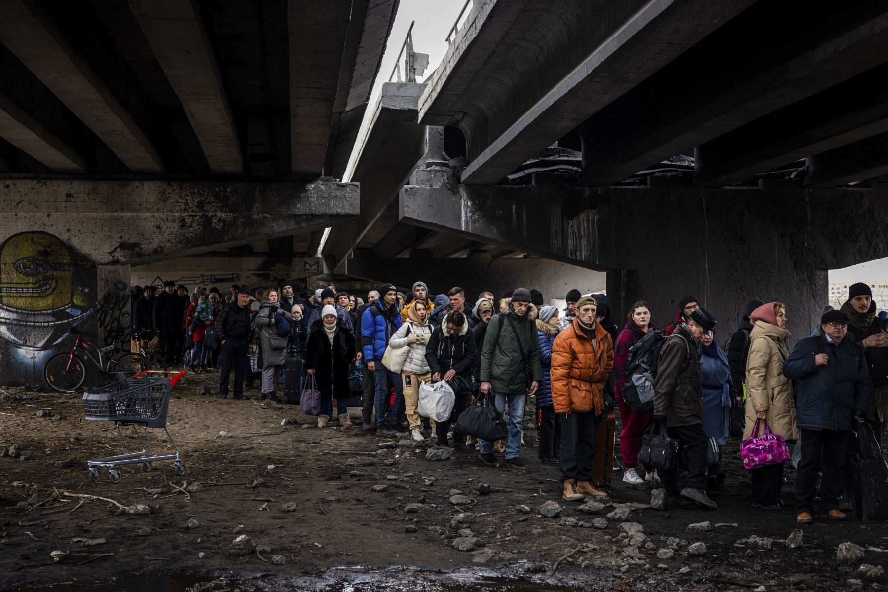 Los evacuados se paran debajo de un puente destruido mientras huyen de la ciudad de Irpin, al noroeste de Kyiv, el 7 de marzo de 2022. Foto: AFP