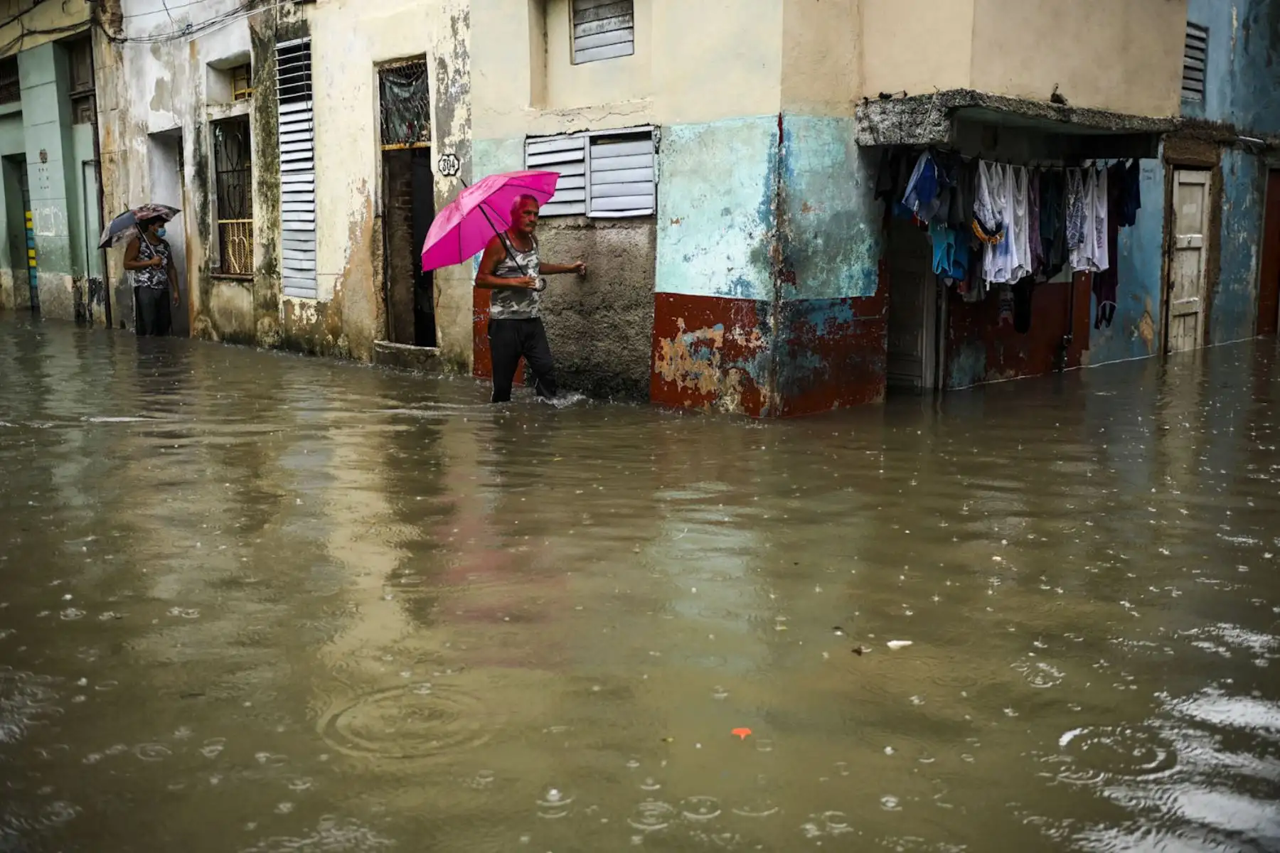 Personas caminan por una calle inundada en La Habana. Los remanentes del huracán Agatha provocan este viernes intensas y persistentes lluvias en las provincias occidentales y centrales de Cuba. Foto: AFP