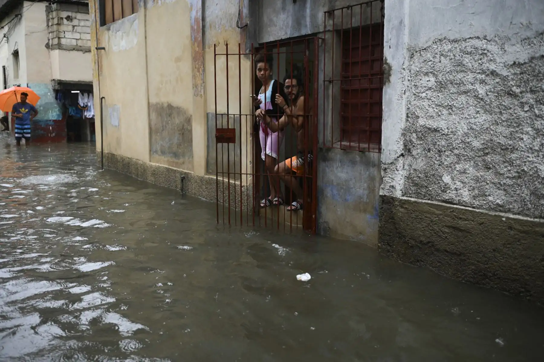 La gente mira una calle inundada desde una casa de La Habana. Los remanentes del huracán Agatha provocan este viernes intensas y persistentes lluvias en las provincias occidentales y centrales de Cuba. Foto: AFP