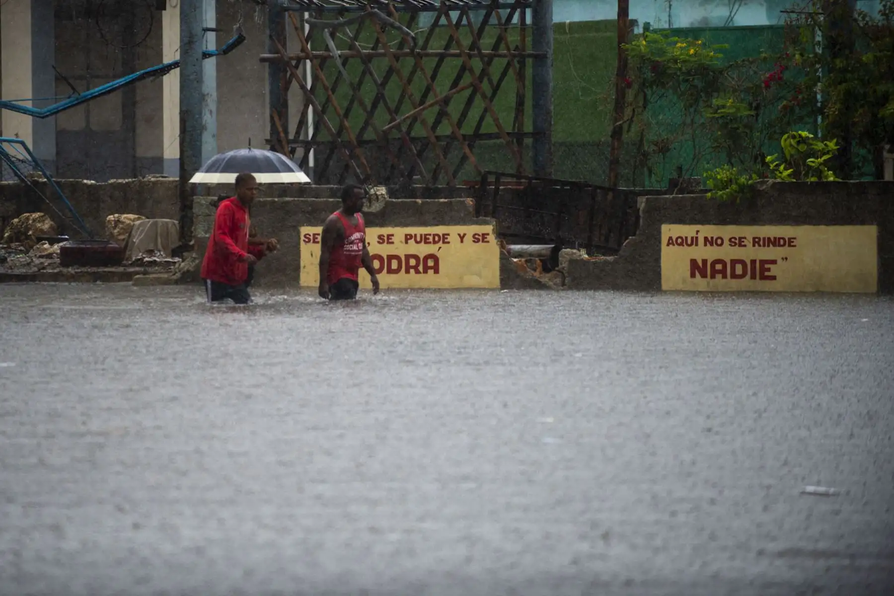 Hombres caminan por una calle inundada en La Habana. Los remanentes del huracán Agatha provocan este viernes intensas y persistentes lluvias en las provincias occidentales y centrales de Cuba. Foto: AFP