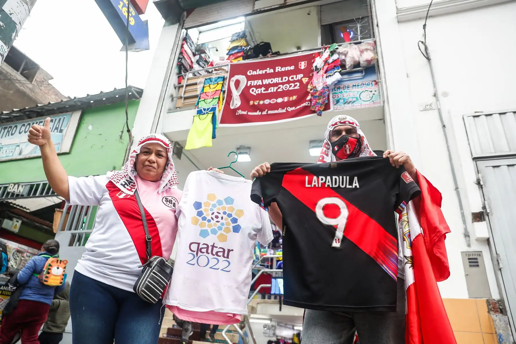 Incrementan las ventas de camisetas de la Selección, en Gamarra, a una semana de disputarse el partido de repechaje rumbo al Mundial Qatar 2022. Vicky y Antonio, muestran la indumentaria que ofrecen en la galería 