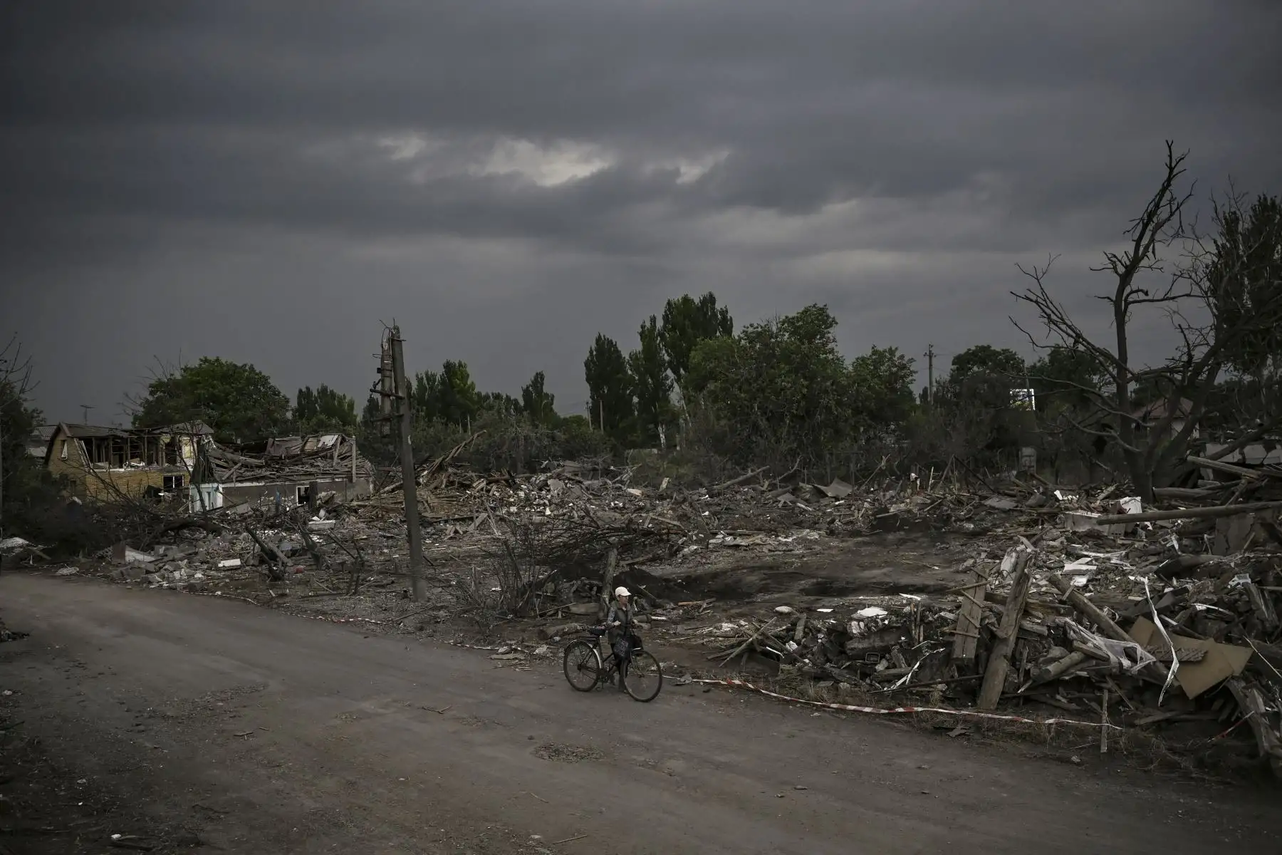 Una anciana con su bicicleta camina junto a los escombros de las casas destruidas en la ciudad de Dobropillya, en la región oriental de Ucrania de Donbas. Foto: AFP