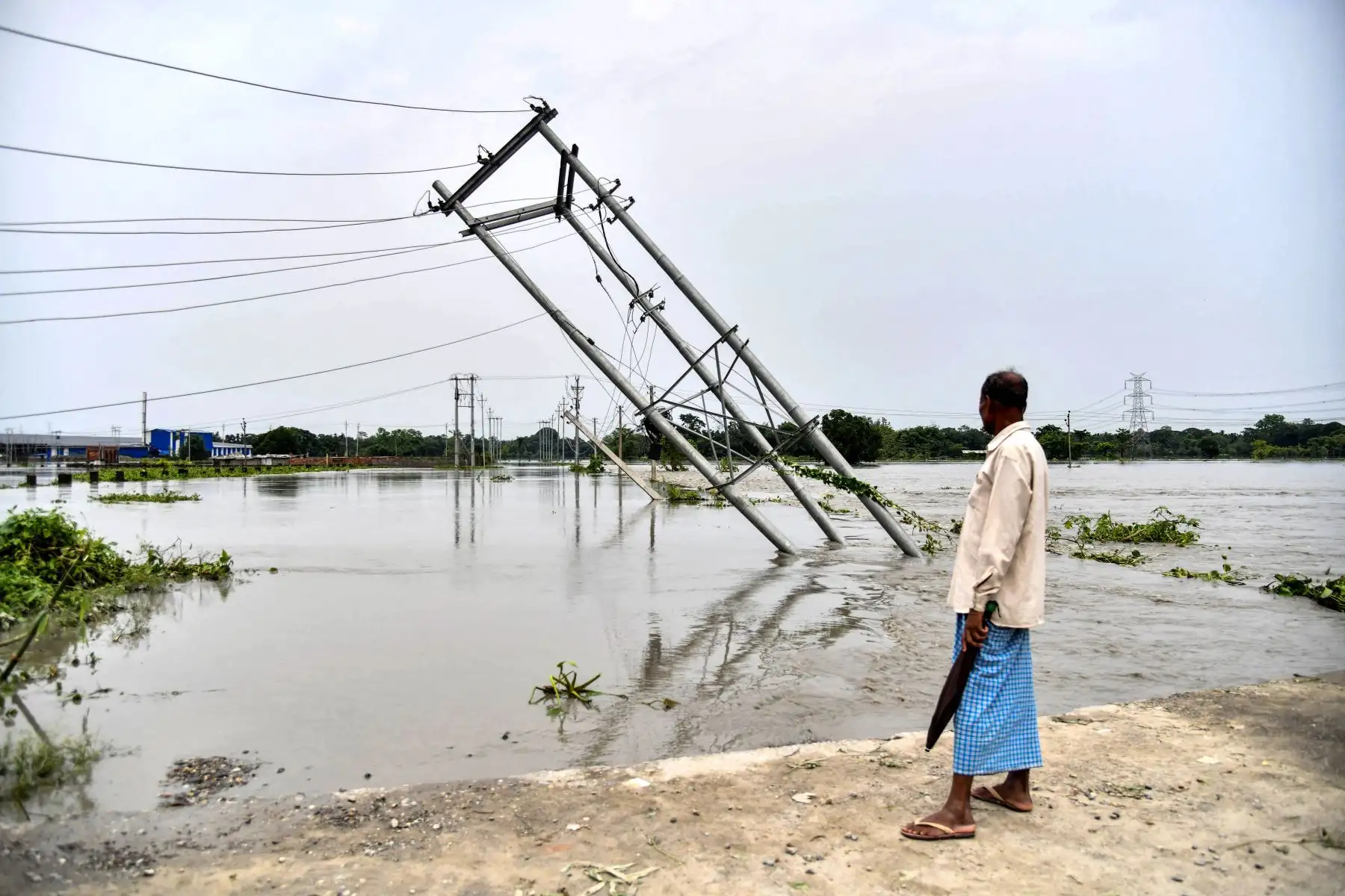 Un hombre mira los pilares eléctricos volcados que fueron dañados por las inundaciones en Rangia del distrito de Kamrup, en el estado indio de Assam.
Foto: AFP