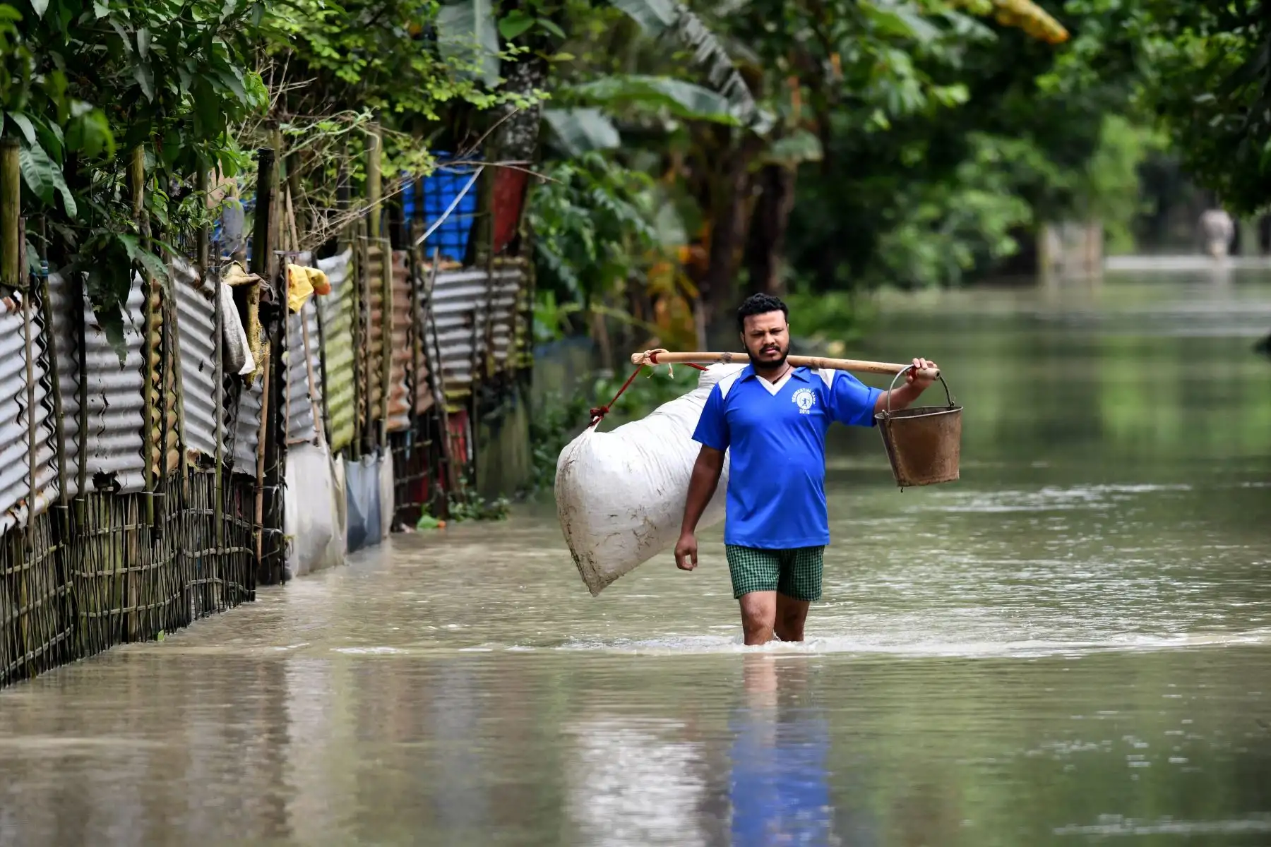 Un hombre vadea las aguas de la inundación en Solmara, en el distrito de Nalbari, en el estado indio de Assam.
Foto: AFP