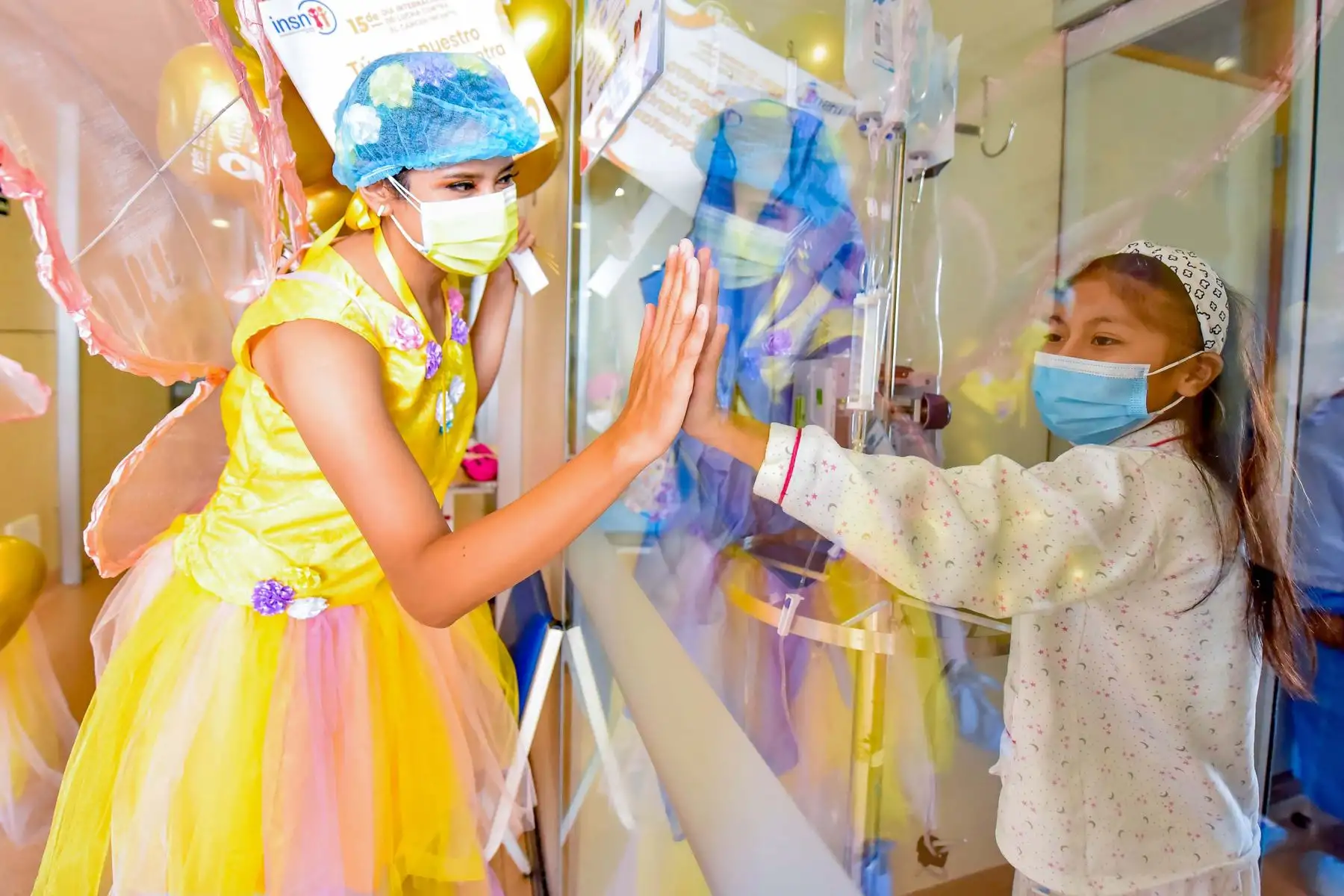 “Unidas por la magia del amor”
Esta puerta les impide unir sus manos, más no su corazón. Es así que la pequeña paciente de Hematología recibe a través del vidrio las buenas vibras y el amor de la joven, que vestida de hada visitó el servicio en el marco del Día Mundial de Lucha contra el Cáncer Infantil. 
Foto: INSN de San Borja