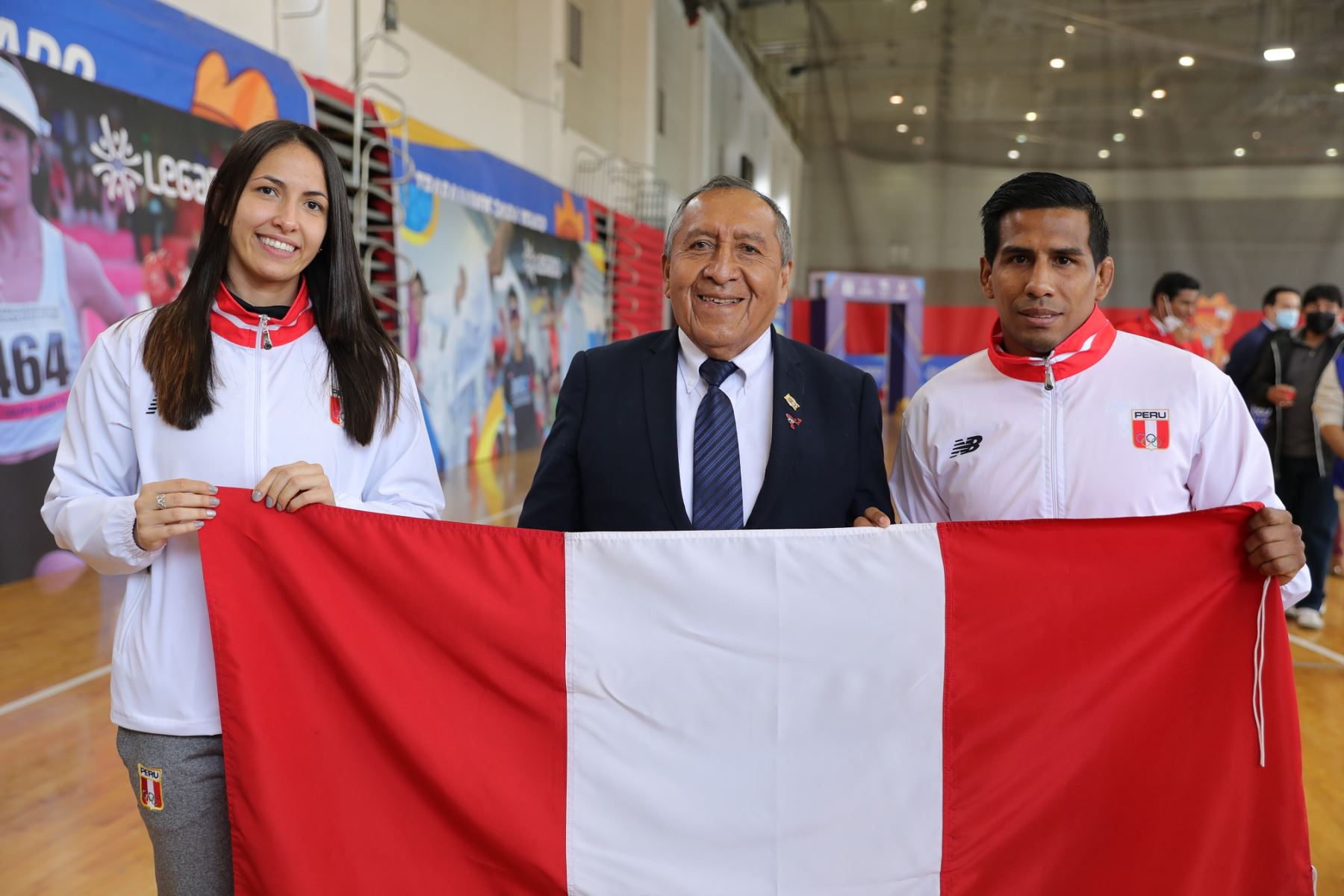 María Luisa Doig y Juan Miguel Postigos posan con la bandera que portarán en los Juegos Bolivarianos Valledupar 2022