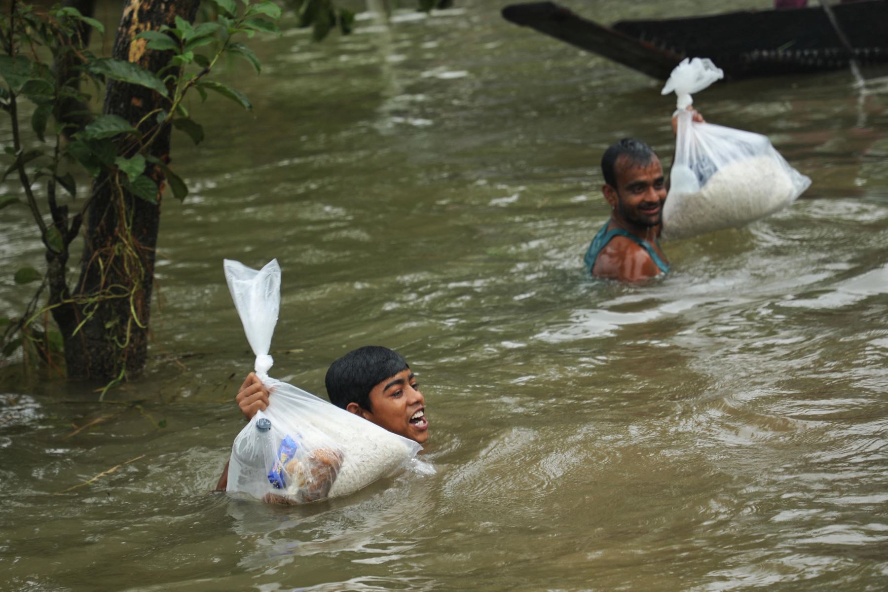 La gente recoge ayuda alimentaria en una zona residencial inundada tras las fuertes lluvias monzónicas en Companiganj. Foto: AFP