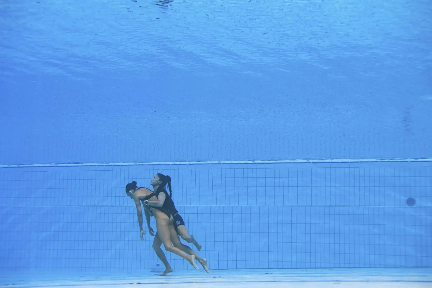 La entrenadora española, Andra Fuentes, nada para salvar a Anita Alvarez del fondo de la piscina durante un incidente en las finales de natación artística libre en solitario de mujeres, durante el Campeonato Mundial Acuático de Budapest 2022. Foto: AFP