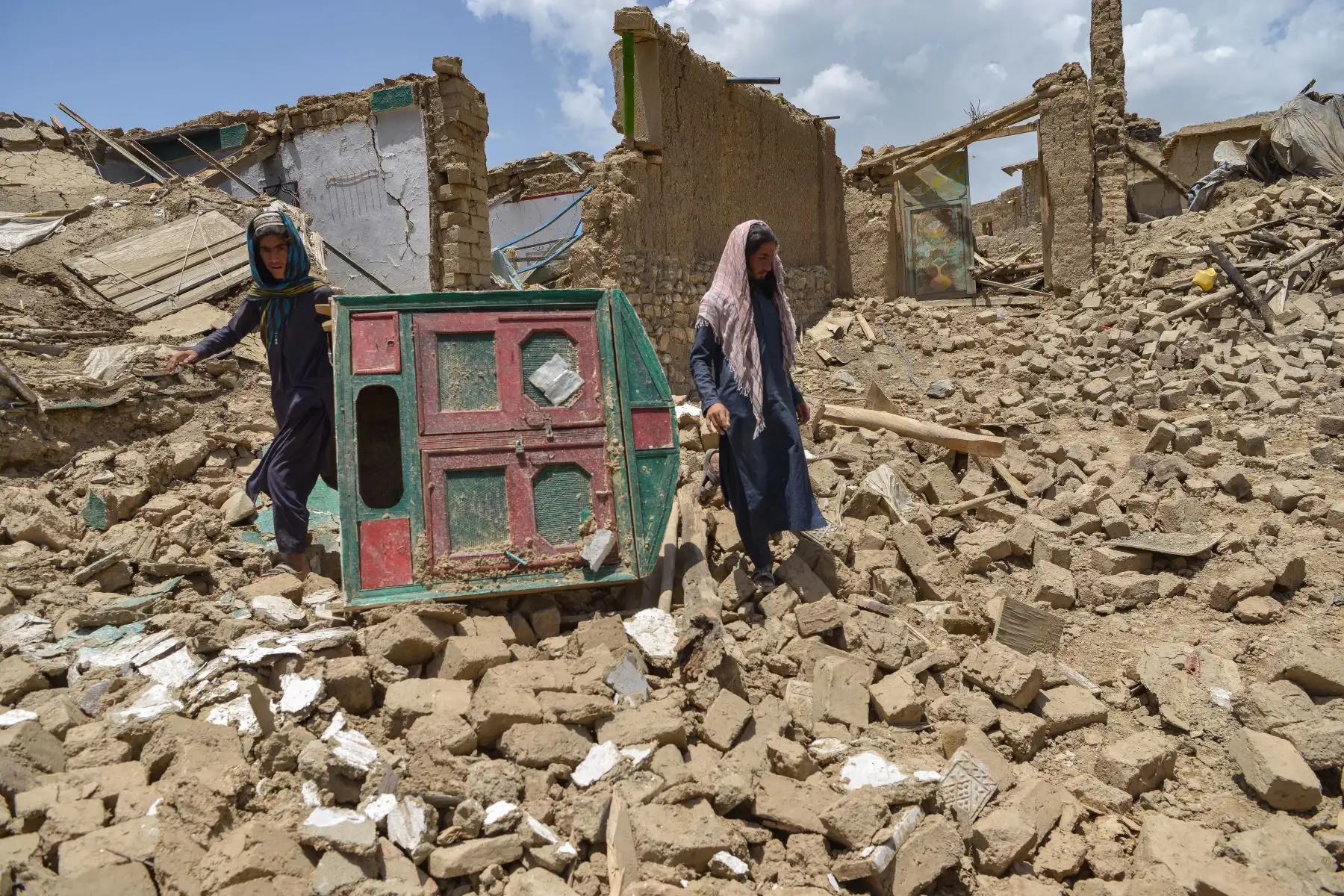 Hombres afganos buscan sus pertenencias entre las ruinas de una casa dañada por un terremoto en el distrito de Bernal, provincia de Paktika. Foto: AFP