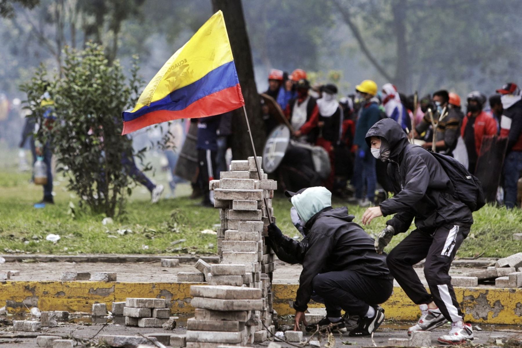 Los manifestantes se paran detrás de una barricada durante los enfrentamientos con la policía antidisturbios en el parque El Ejido, en Quito. AFP