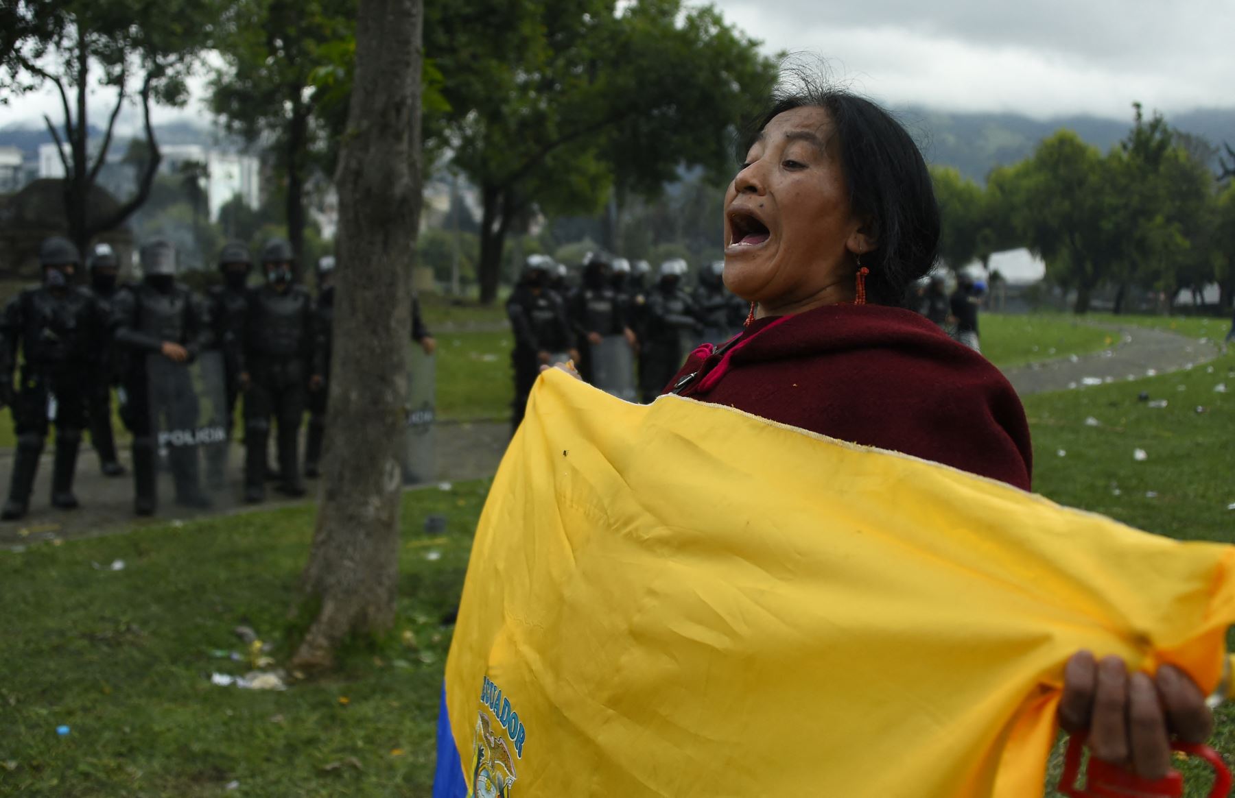 Una mujer indígena sostiene una bandera ecuatoriana frente a la policía antidisturbios en el parque El Ejido, en Quito. AFP