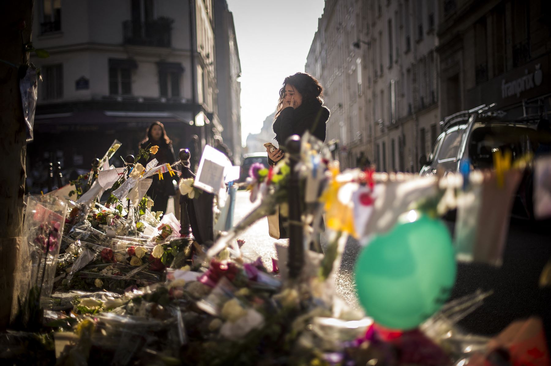 En una foto de archivo tomada el 23 de noviembre del 2015, se puede apreciar a una persona que llora mientras se para en un memorial improvisado para rendir homenaje a las víctimas de una serie de ataques mortales en París, frente al restaurante Casa Nostra en París. Foto: AFP