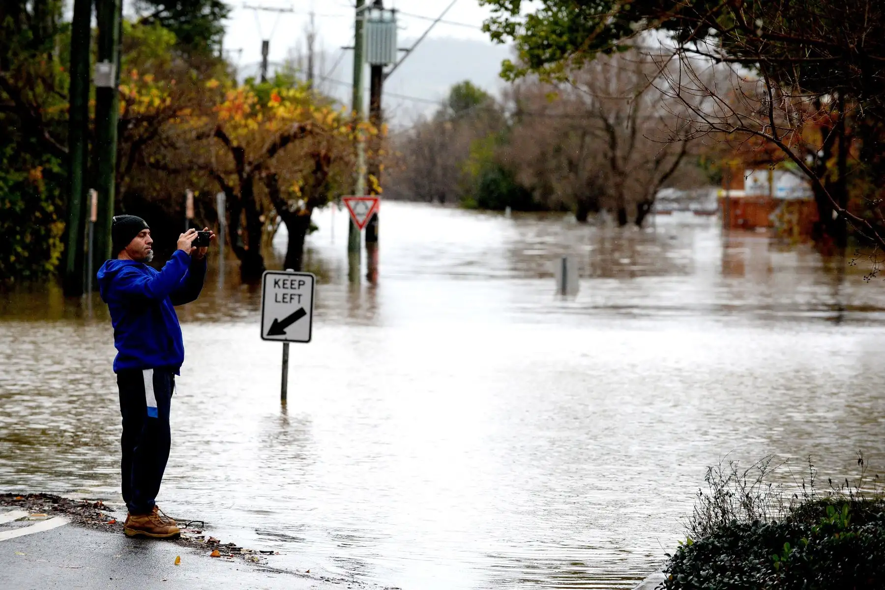 Un hombre toma fotografías de las calles inundadas debido a las lluvias torrenciales en el suburbio de Camden en Sydney.
Foto: AFP
