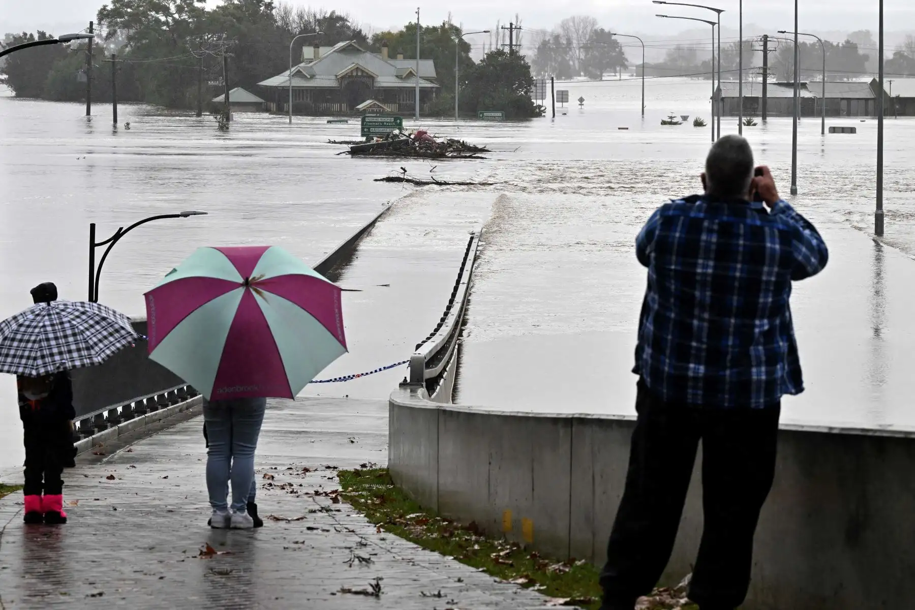Los residentes miran hacia los edificios inundados junto al antiguo puente de Windsor a lo largo del río Hawkesbury al noroeste de Sydney. Foto: AFP