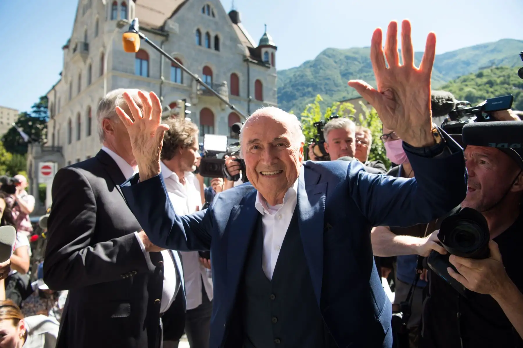 El ex presidente de la FIFA, Joseph Blatter, rodeado de representantes de los medios de comunicación, saluda a la prensa este viernes frente al Tribunal Penal Federal Suizo tras conocerse el veredicto de absolución en Bellinzona. La Fiscalía Federal acusó de fraude al ex presidente de la FIFA, Joseph Blatter, y al ex presidente de la UEFA, Michel Platini, por un pago sospechoso de dos millones. 
Foto: EFE