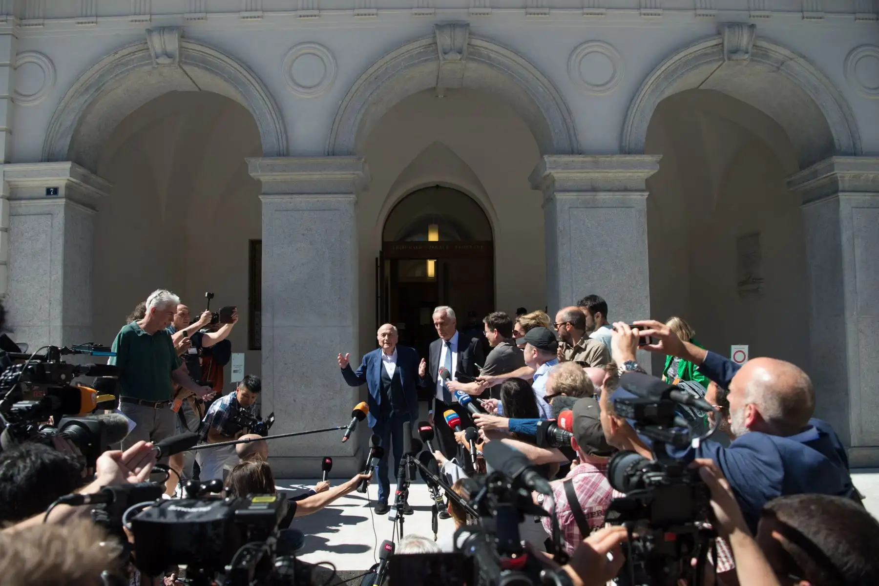 El ex presidente de la FIFA, Joseph Blatter, rodeado de representantes de los medios de comunicación, saluda a la prensa este viernes frente al Tribunal Penal Federal Suizo tras conocerse el veredicto de absolución en Bellinzona. La Fiscalía Federal acusó de fraude al ex presidente de la FIFA, Joseph Blatter, y al ex presidente de la UEFA, Michel Platini, por un pago sospechoso de dos millones. 
Foto: EFE