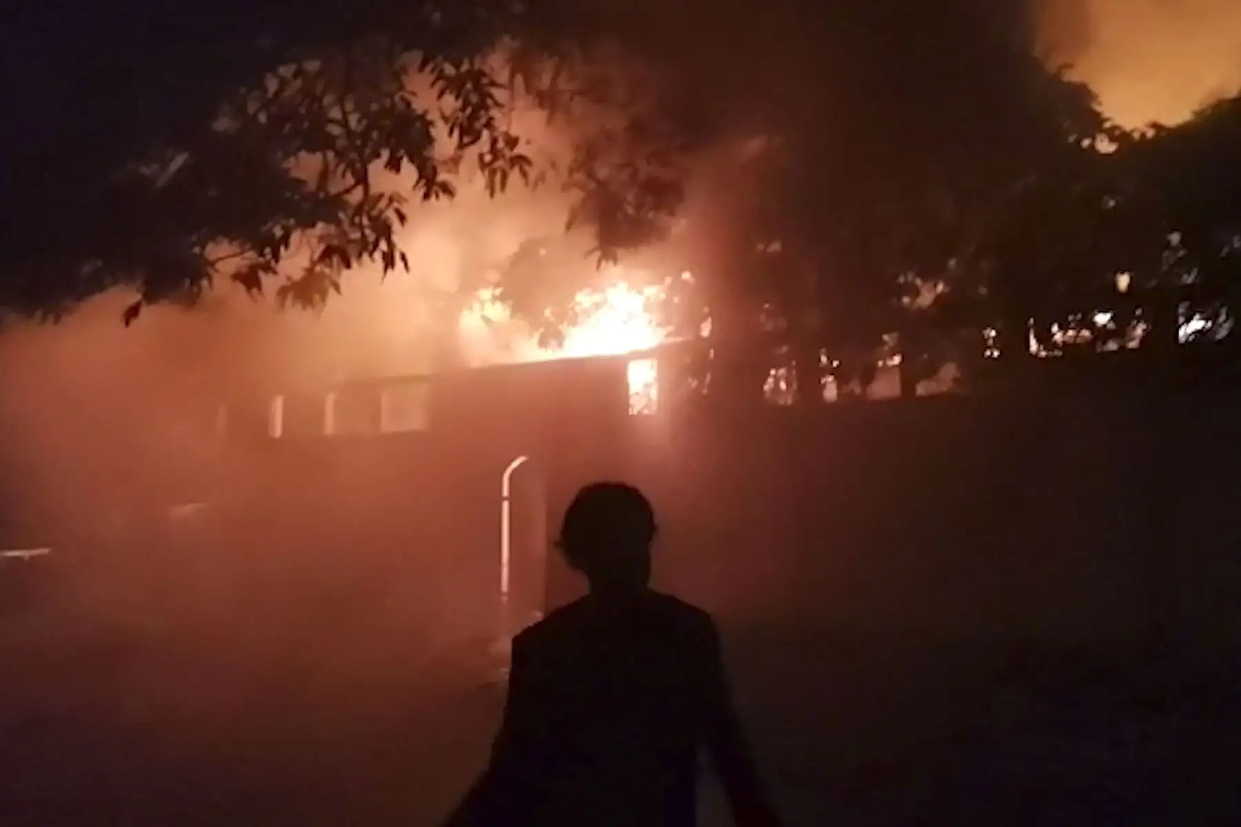 Esta captura de pantalla tomada de imágenes de AFPTV  muestra a un hombre caminando frente a la residencia del primer ministro de Sri Lanka después de que se incendiara durante las protestas en Colombo. 
Foto: AFP