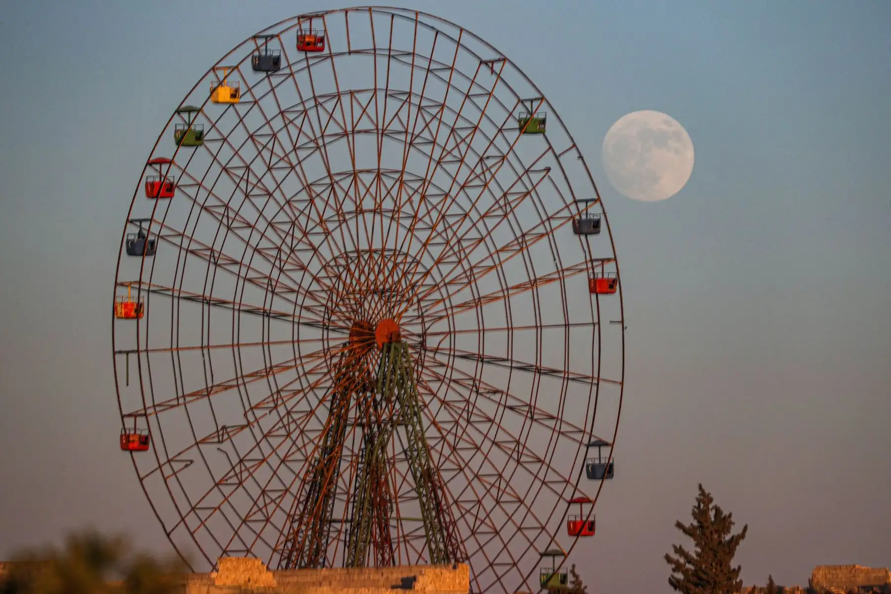 La luna creciente se eleva detrás de un parque de diversiones para niños abandonado cerca de al-Nayrab, en Siria. La Superluna de julio. Foto: AFP