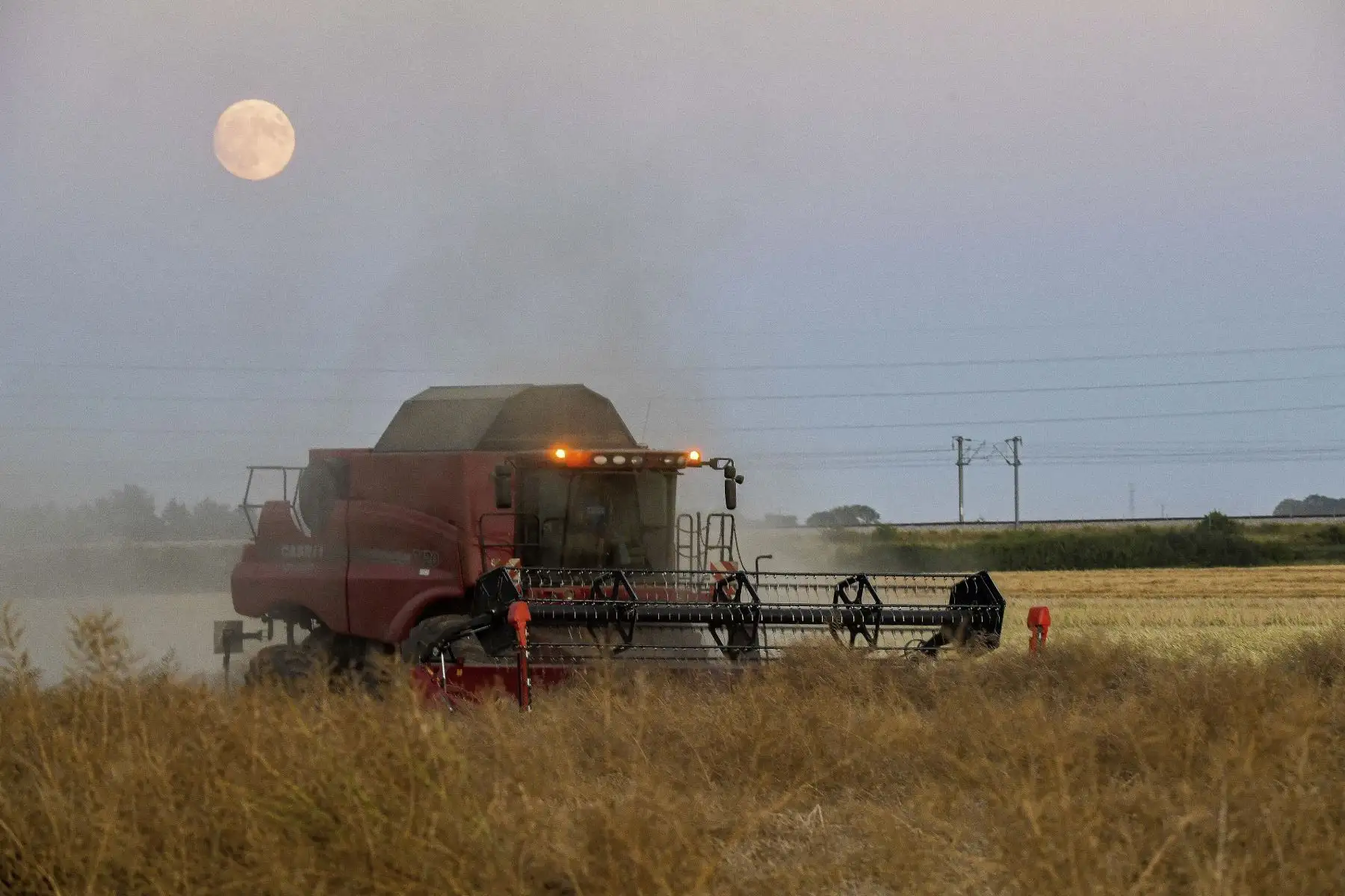 La Superluna se eleva mientras se ve una cosechadora en un parque eólico, en Beauvilliers, cerca de Allonnes, centro de Francia. Foto: AFP