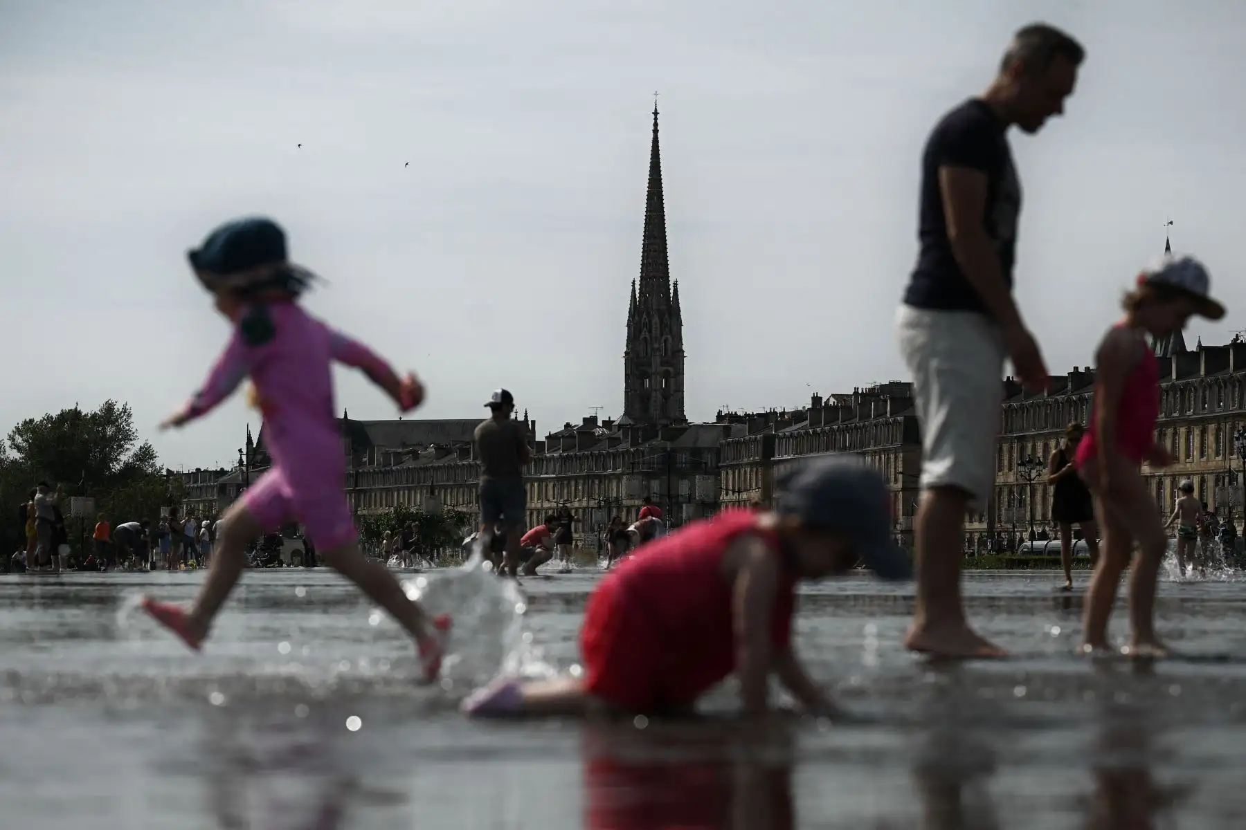 Los niños se refrescan mientras juegan en la fuente de agua "Miroir d