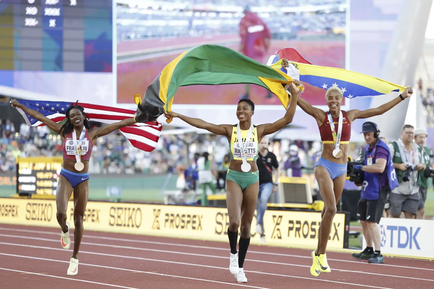 La medallista de bronce Tori+Franklin de EE. UU., la medallista de plata Shanieka+Ricketts de Jamaica y la medallista de oro Yulimar+Rojas de Venezuela celebran en la pista al final de la final de triple salto femenino en el Campeonato Mundial de Atletismo Oregon22 en Hayward Field.
Foto: EFE