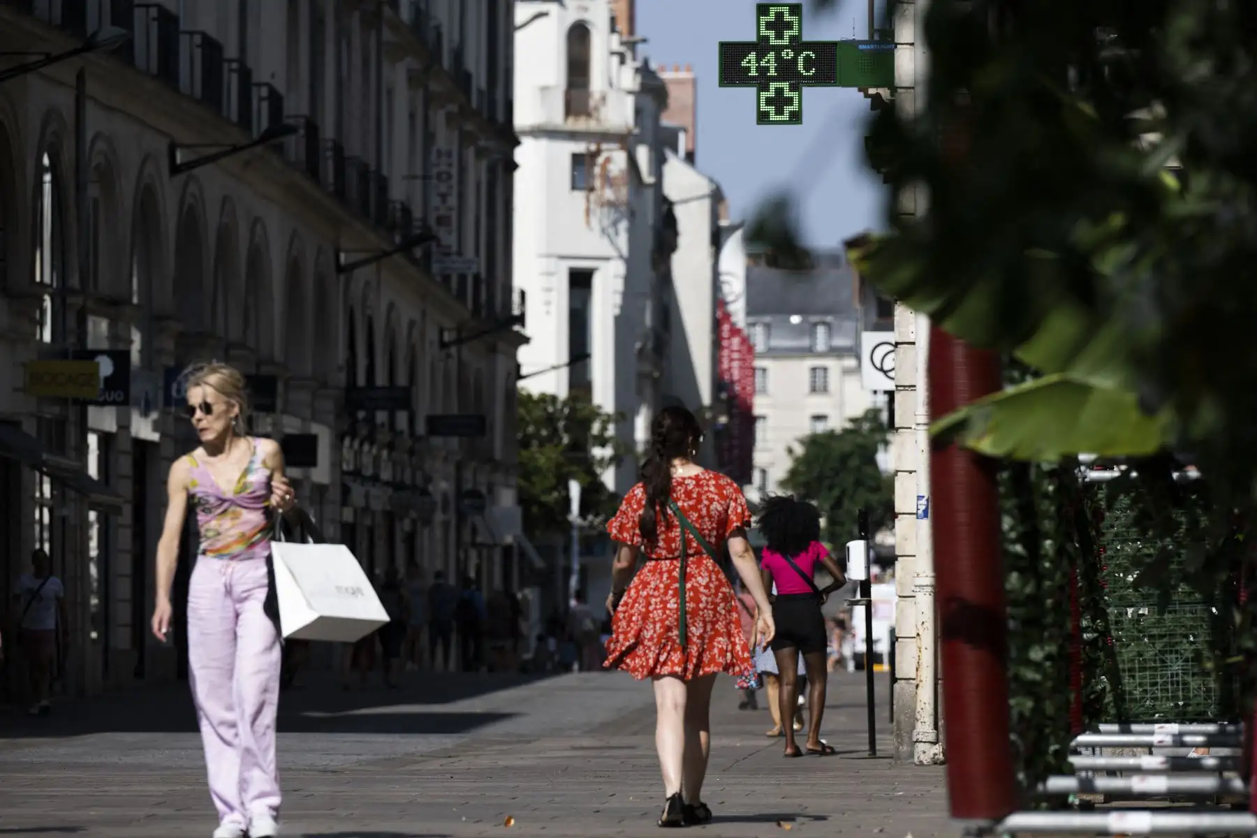 La gente camina por una calle en Nantes mientras un letrero iluminado muestra una temperatura de 44 grados centígrados. Foto: AFP