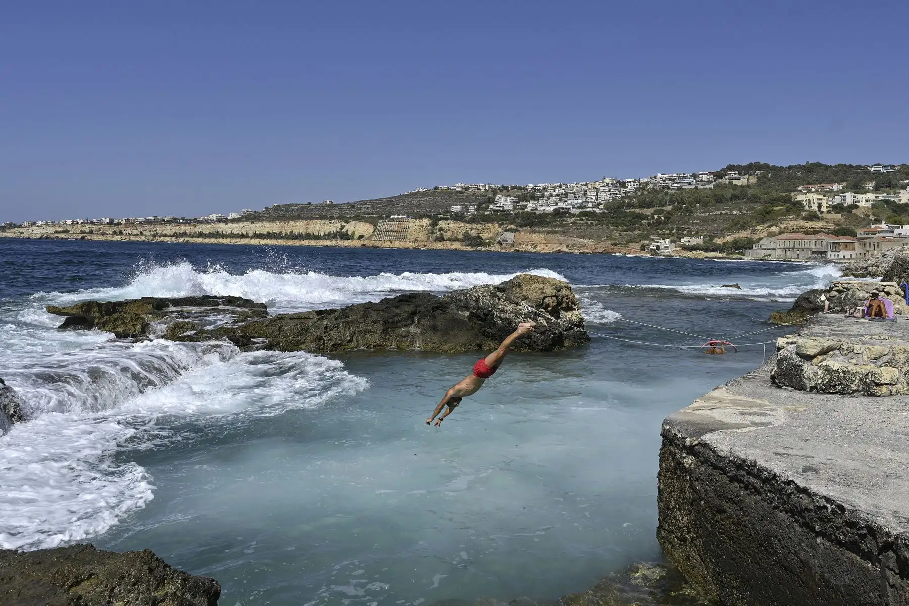 Un hombre se sumerge en una piscina natural en medio de fuertes olas en Chania, en la isla de Creta, Grecia. Foto: AFP