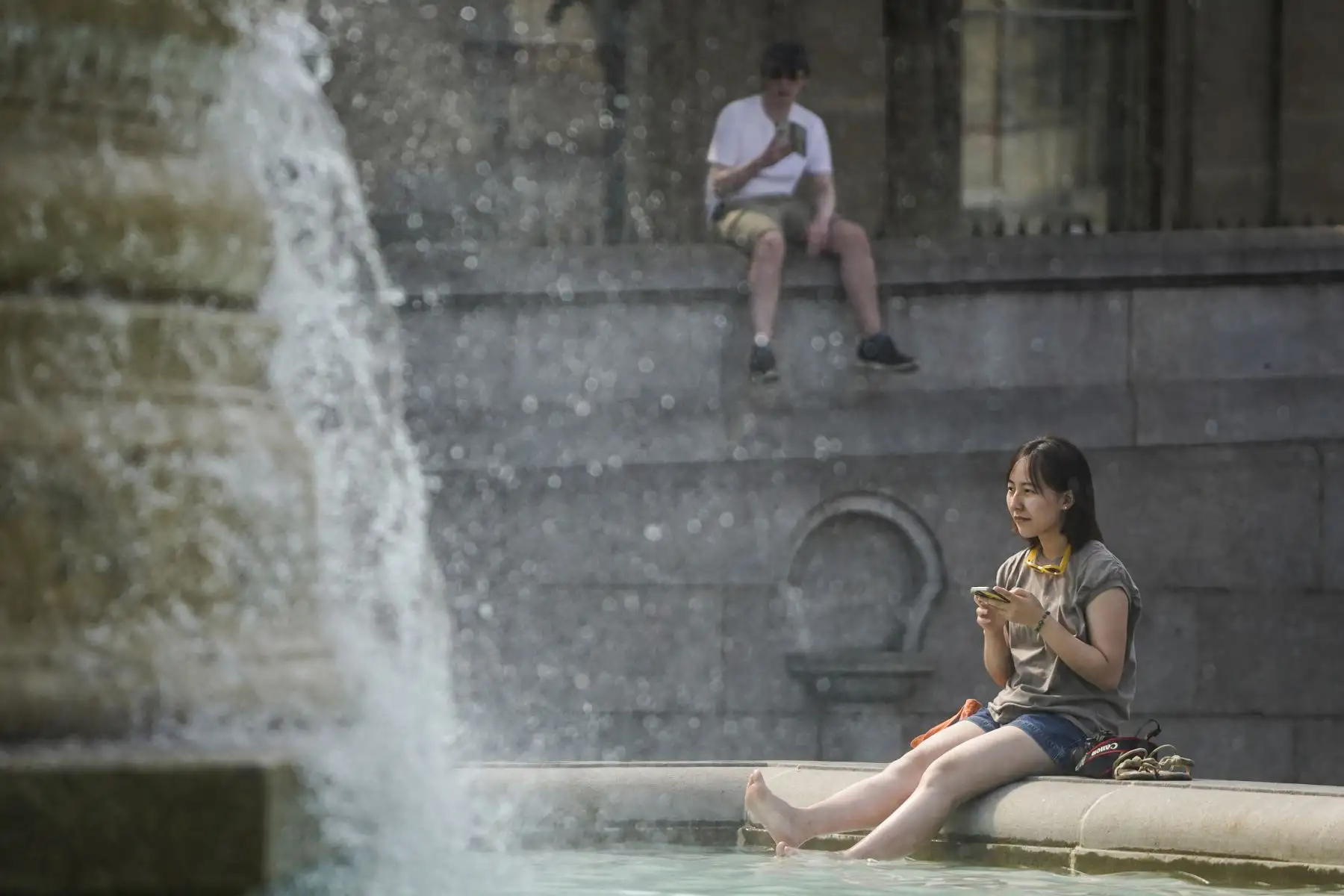 Una mujer se refresca sumergiendo sus pies en la fuente de Trafalgar Square, en el centro de Londres, el mientras el país experimenta una ola de calor extremo. Foto: AFP