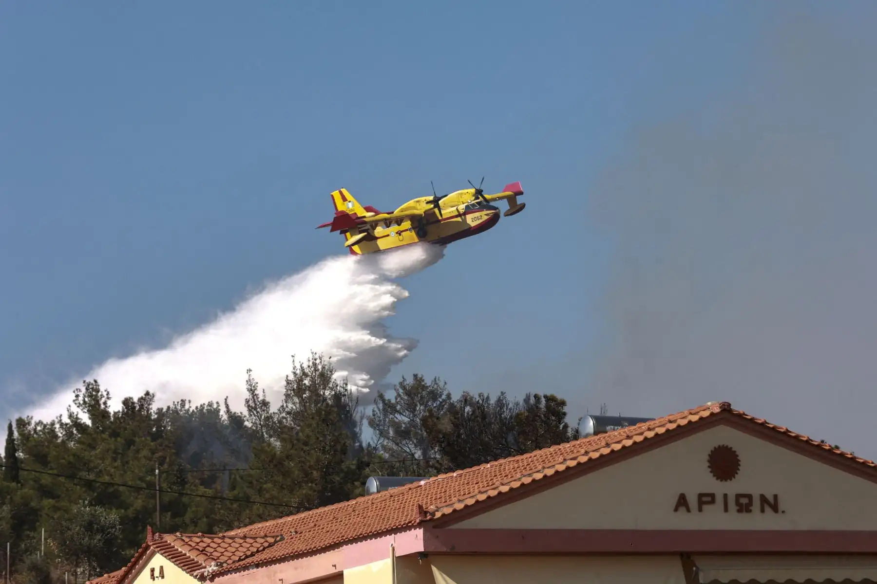 Un avión de extinción de incendios de Canada Air arroja agua sobre el incendio forestal que se acerca a casas y hoteles en el centro turístico costero de Vatera, en la isla oriental de Lesbos.
Foto: AFP