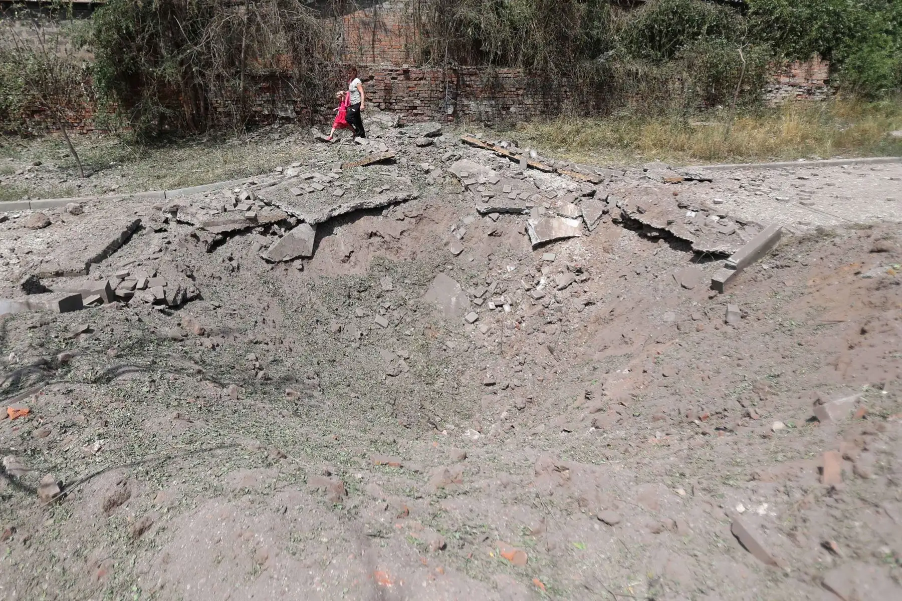 Una mujer y una niña pasan junto al cráter de un misil después de un ataque en la ciudad de Kostyantynivka, región de Donetsk. Foto: AFP