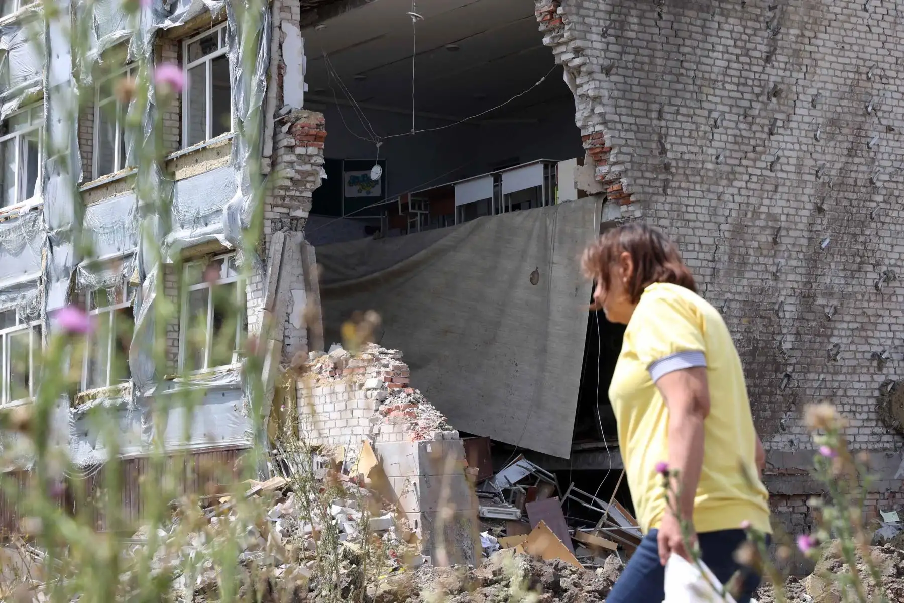Una mujer pasa frente a una escuela parcialmente destruida como resultado de un ataque con misiles en la ciudad de Kostyantynivka, región de Donetsk. Foto: AFP